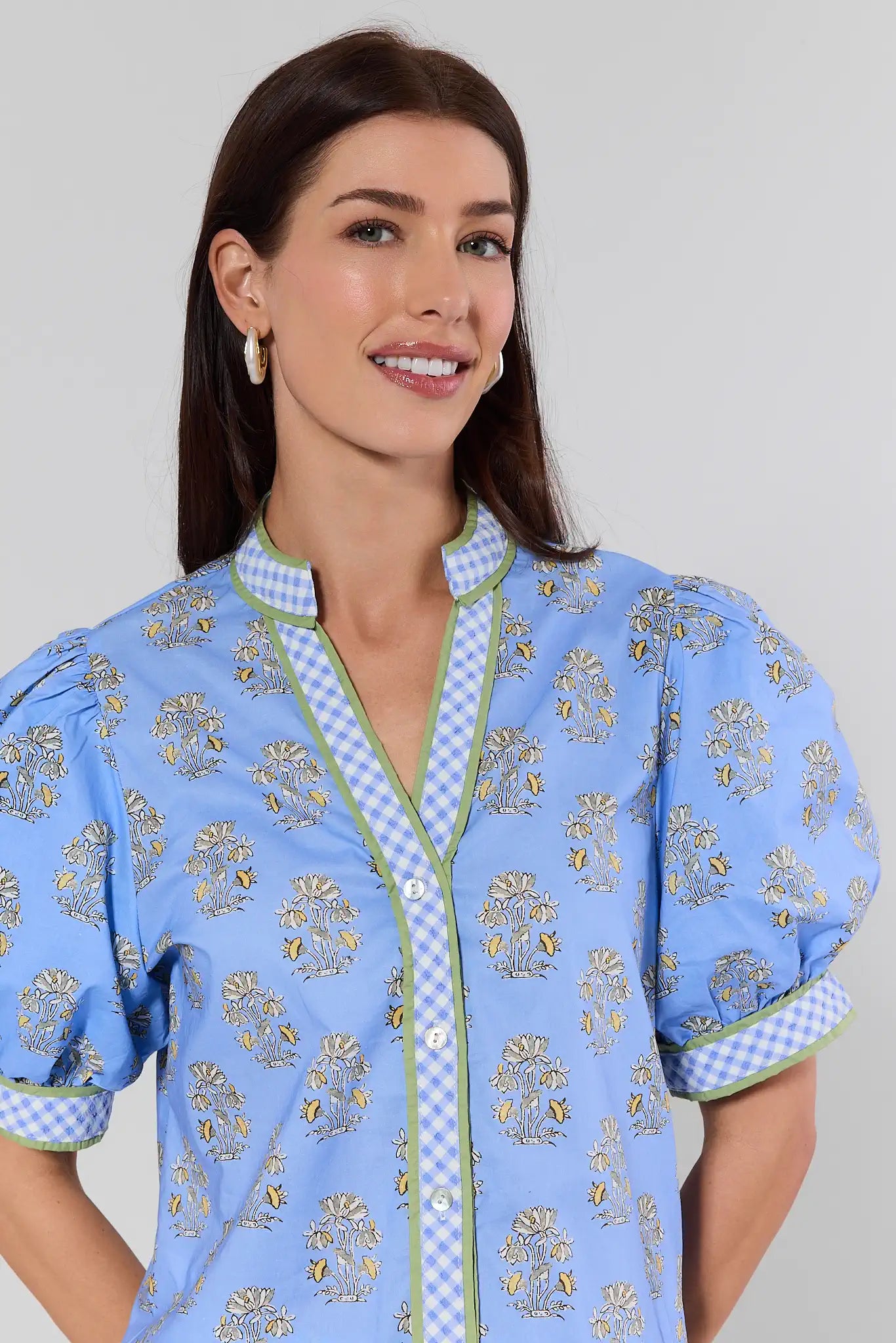 Woman wearing a blue floral patterned shirt with a white background