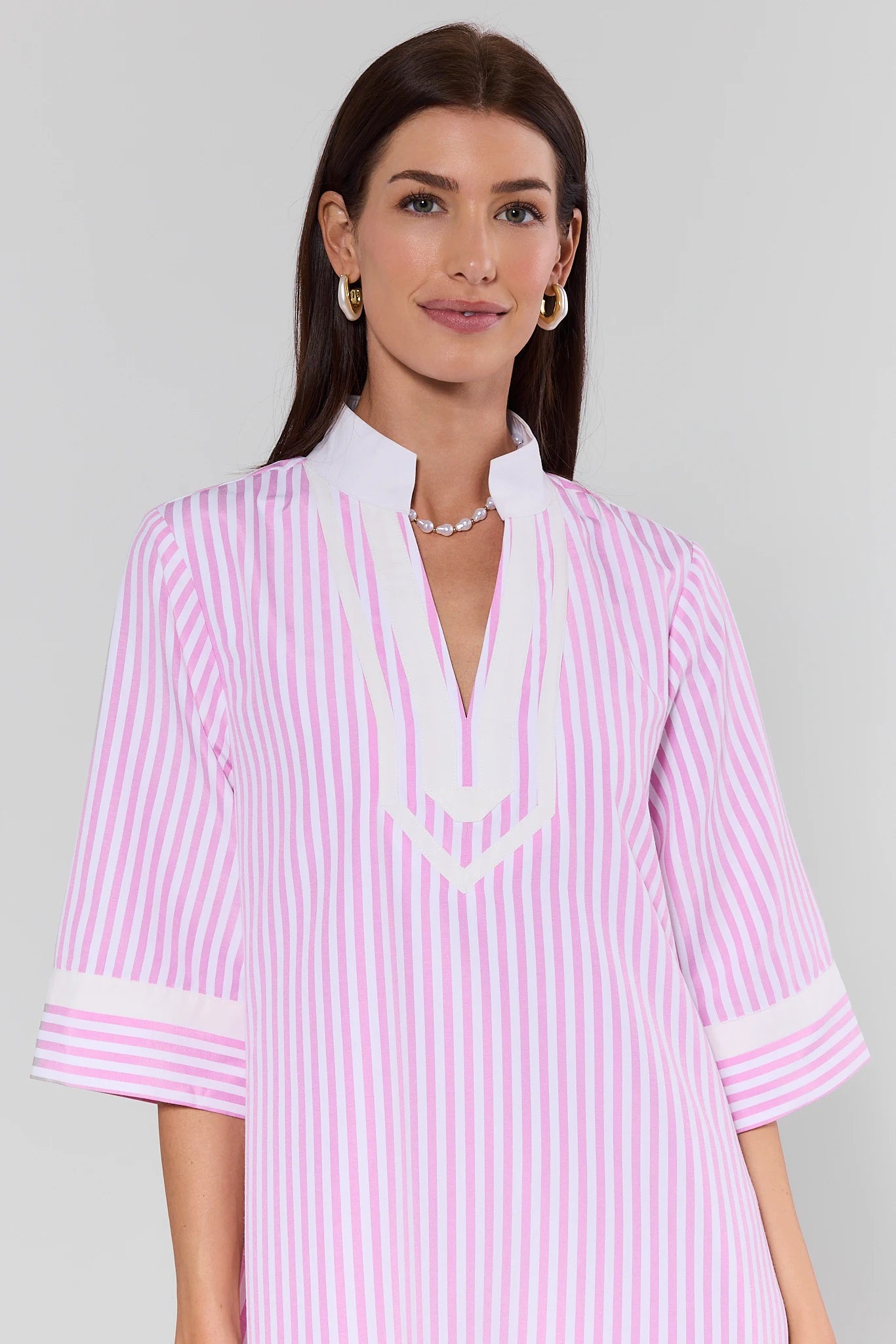 Woman wearing a pink and white striped dress with a plain background