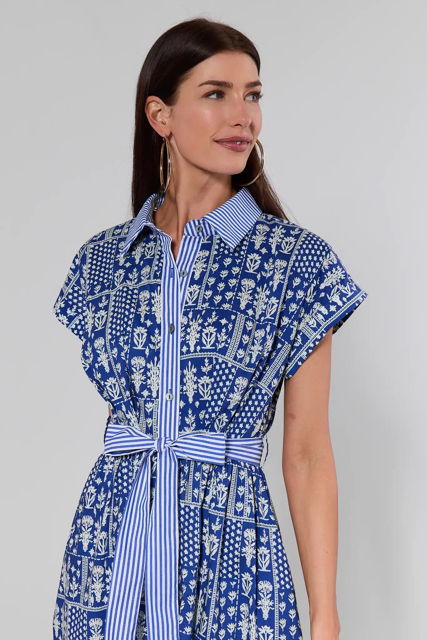 Woman wearing a blue and white patterned dress against a plain background
