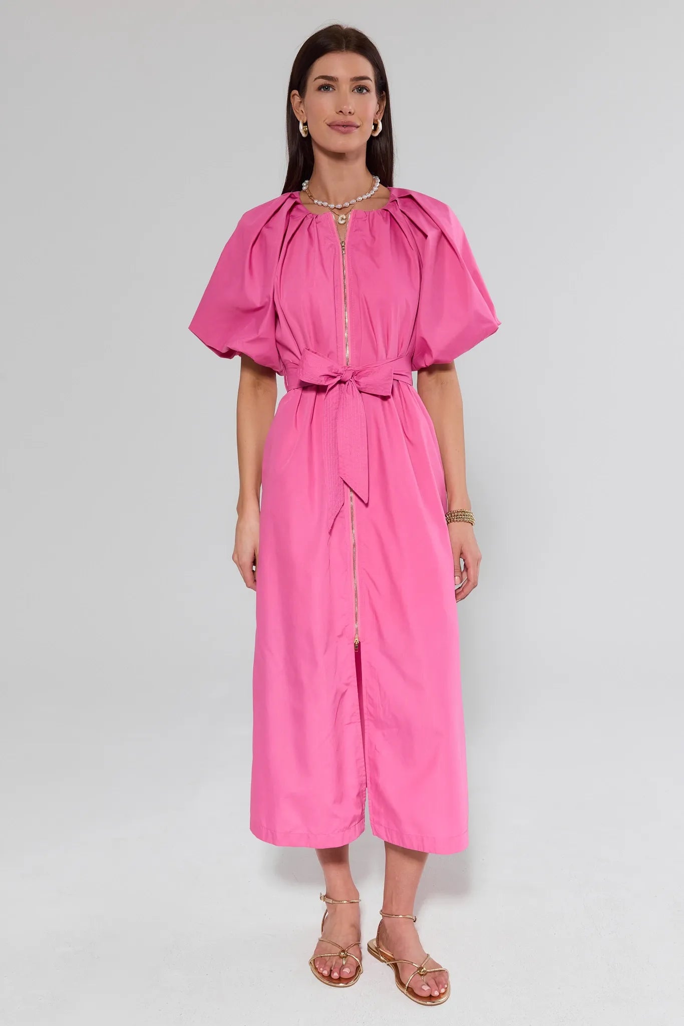 Woman wearing a pink dress with puffed sleeves on a white background