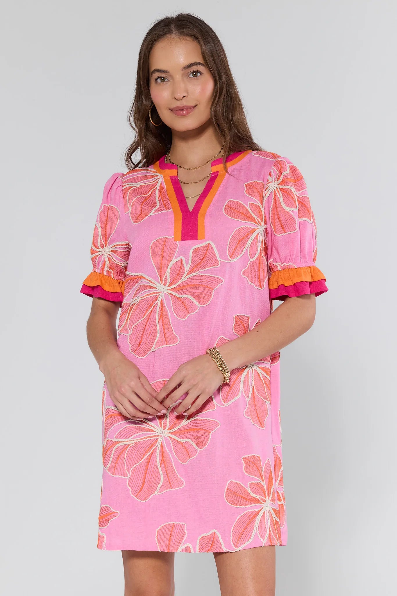 Woman wearing a pink floral dress with orange accents on a white background