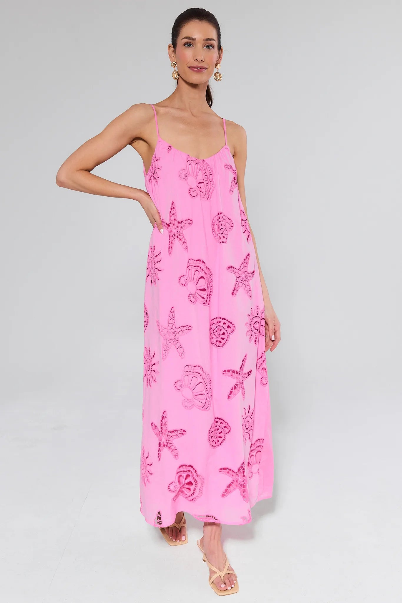 Woman wearing a pink dress with shell patterns on a white background