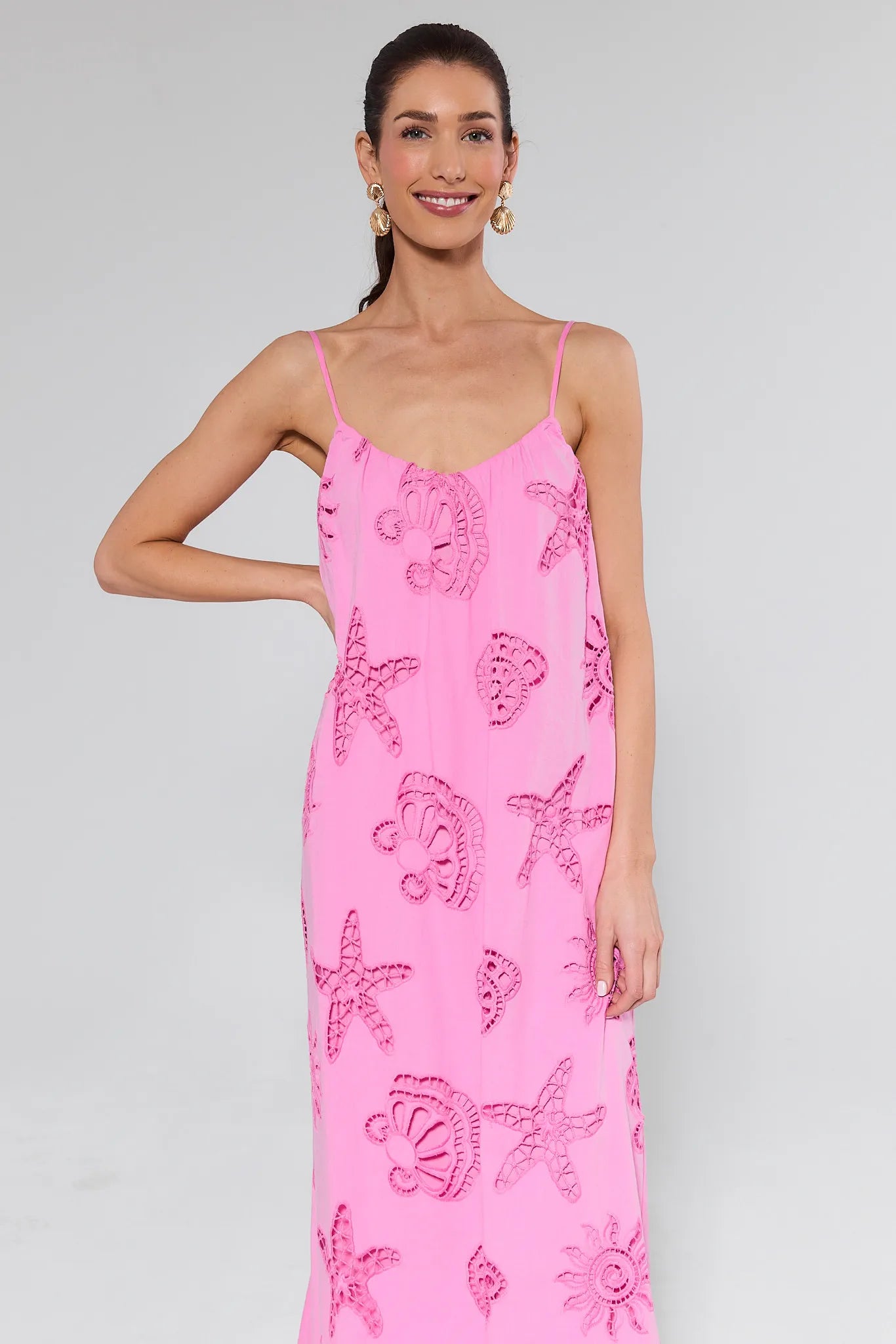 Woman wearing a pink dress with starfish patterns on a plain background