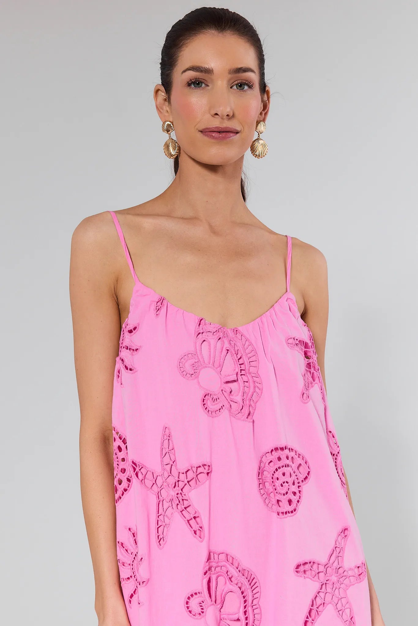 Woman wearing a pink dress with shell patterns on a gray background