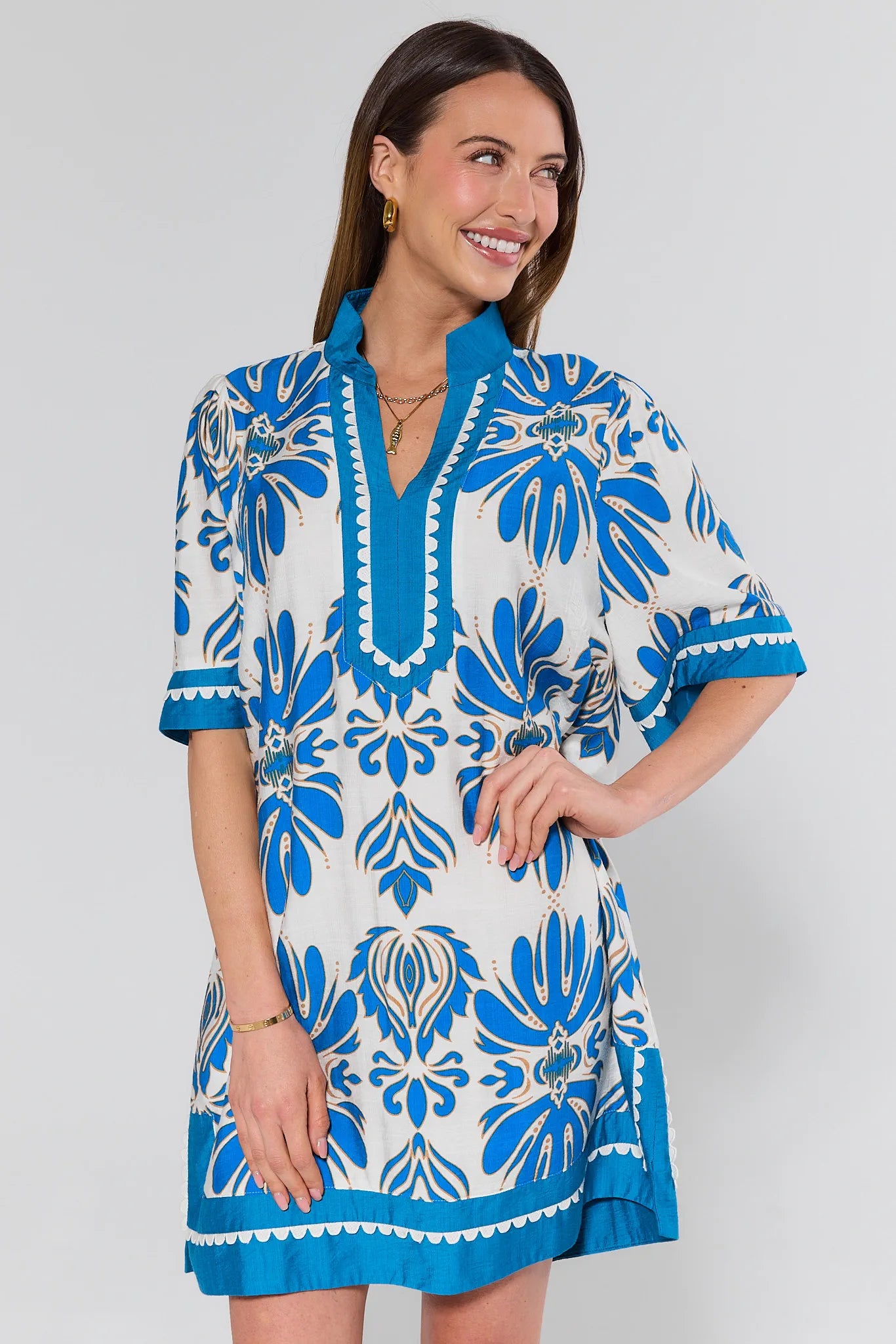 Woman wearing a blue and white patterned dress against a plain background