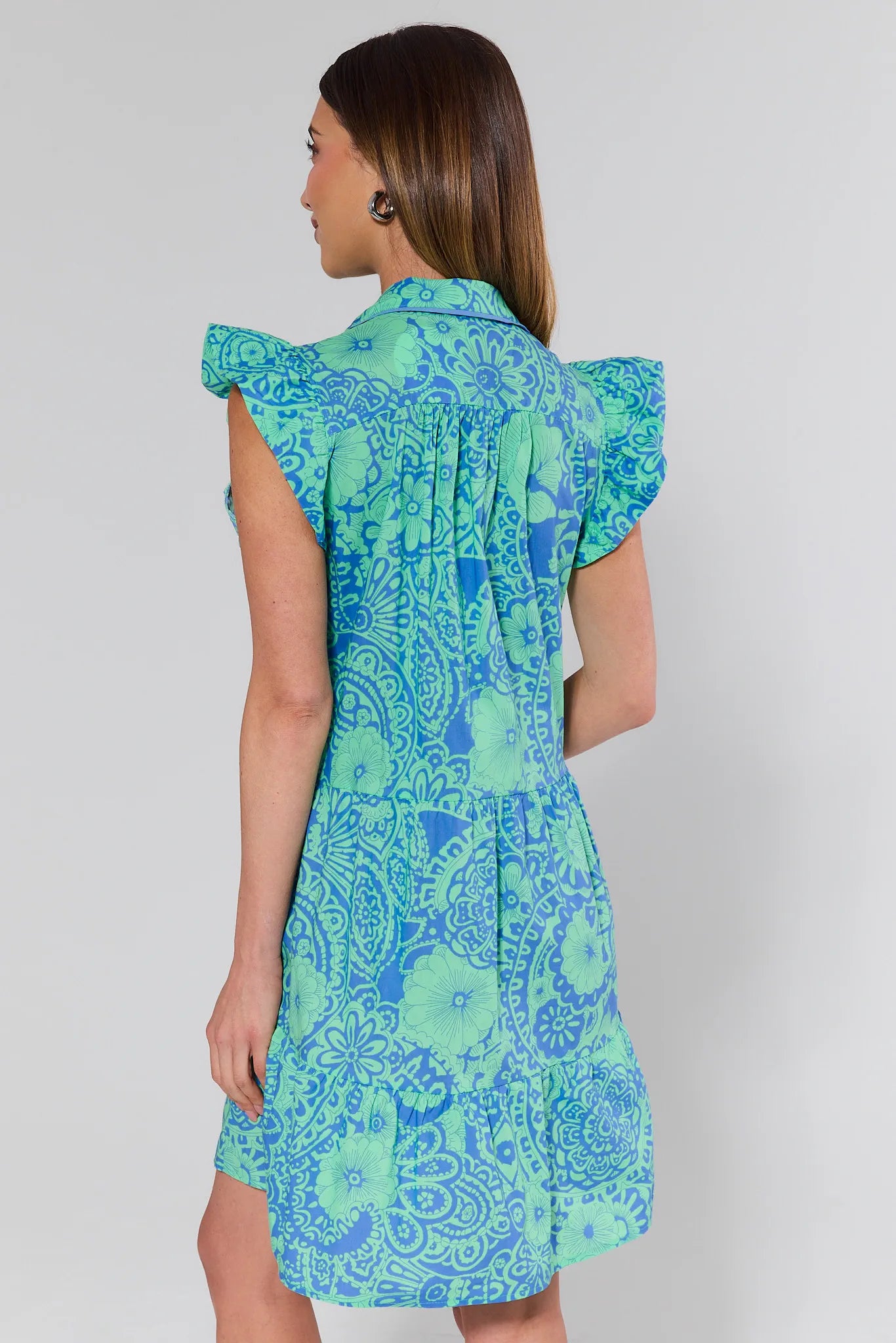 Woman wearing a blue and green patterned dress on a white background