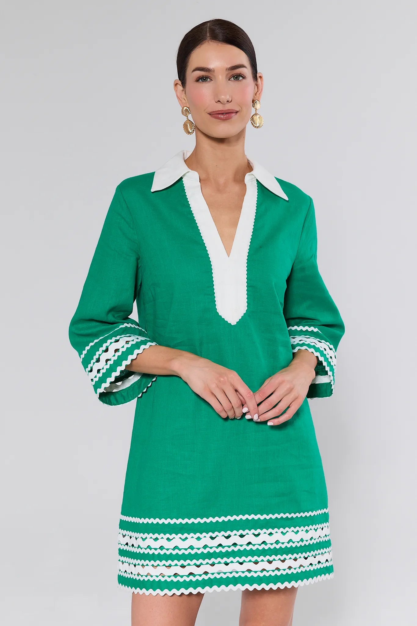 Woman wearing a green dress with white accents on a plain background