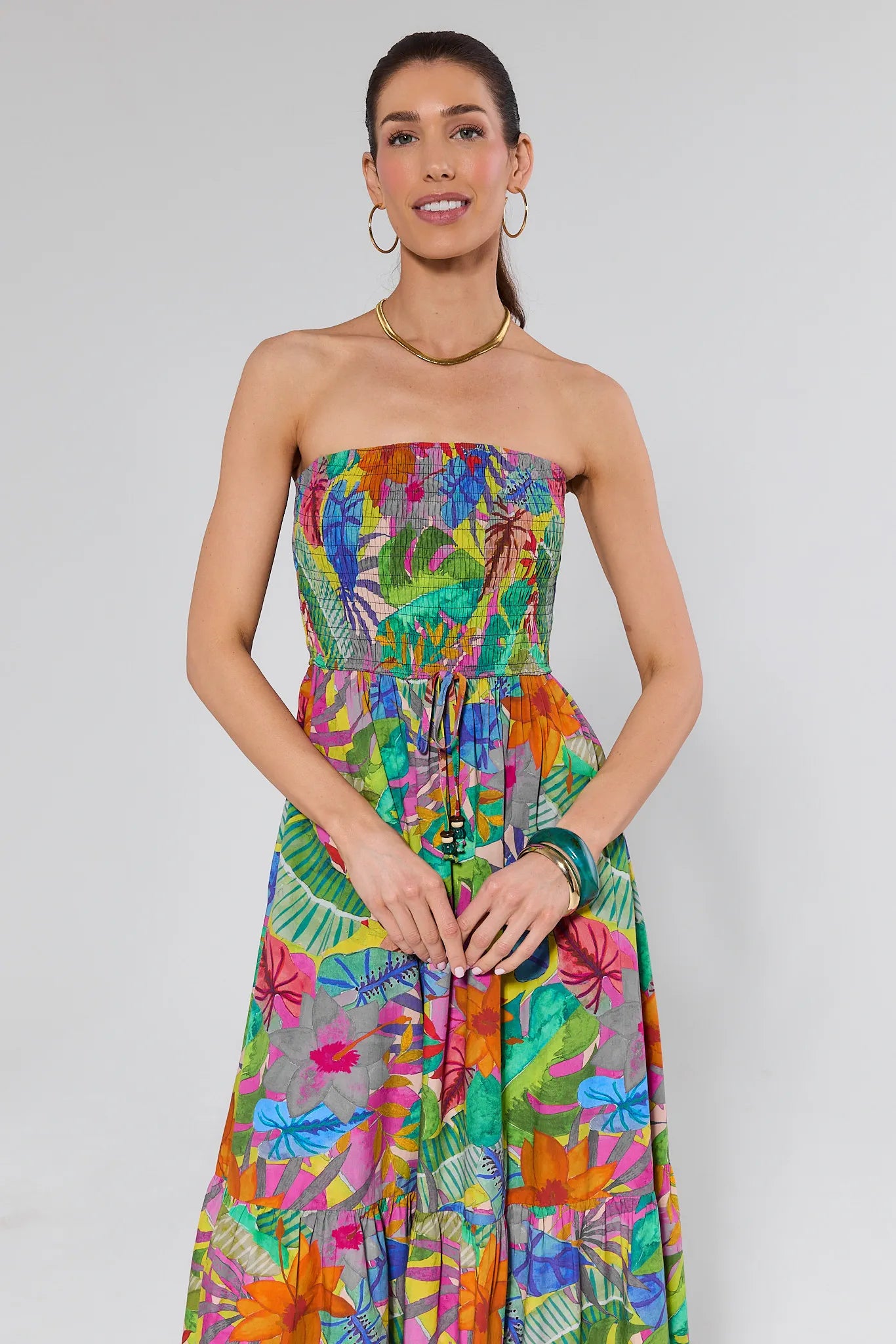 Woman wearing a colorful strapless dress with a floral pattern on a white background