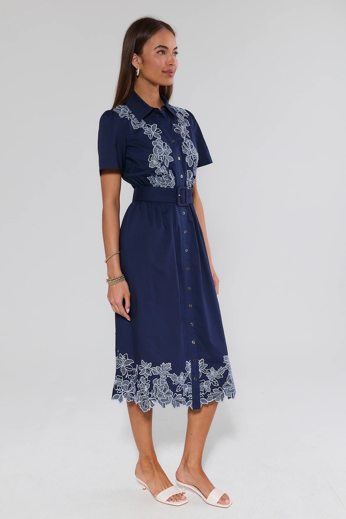 Woman wearing a navy dress with lace details on a white background