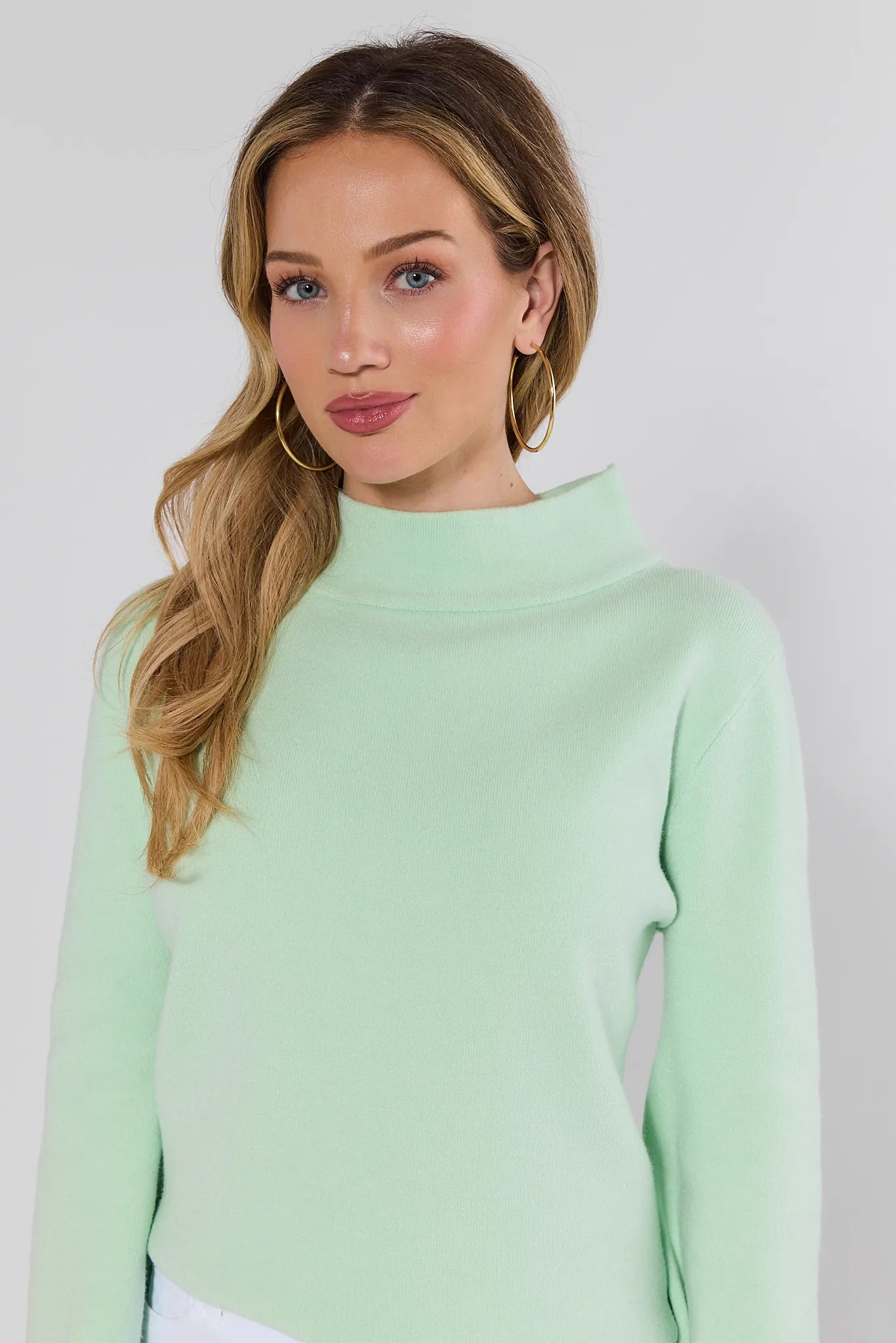 woman wearing light green jackie sweater on a white background