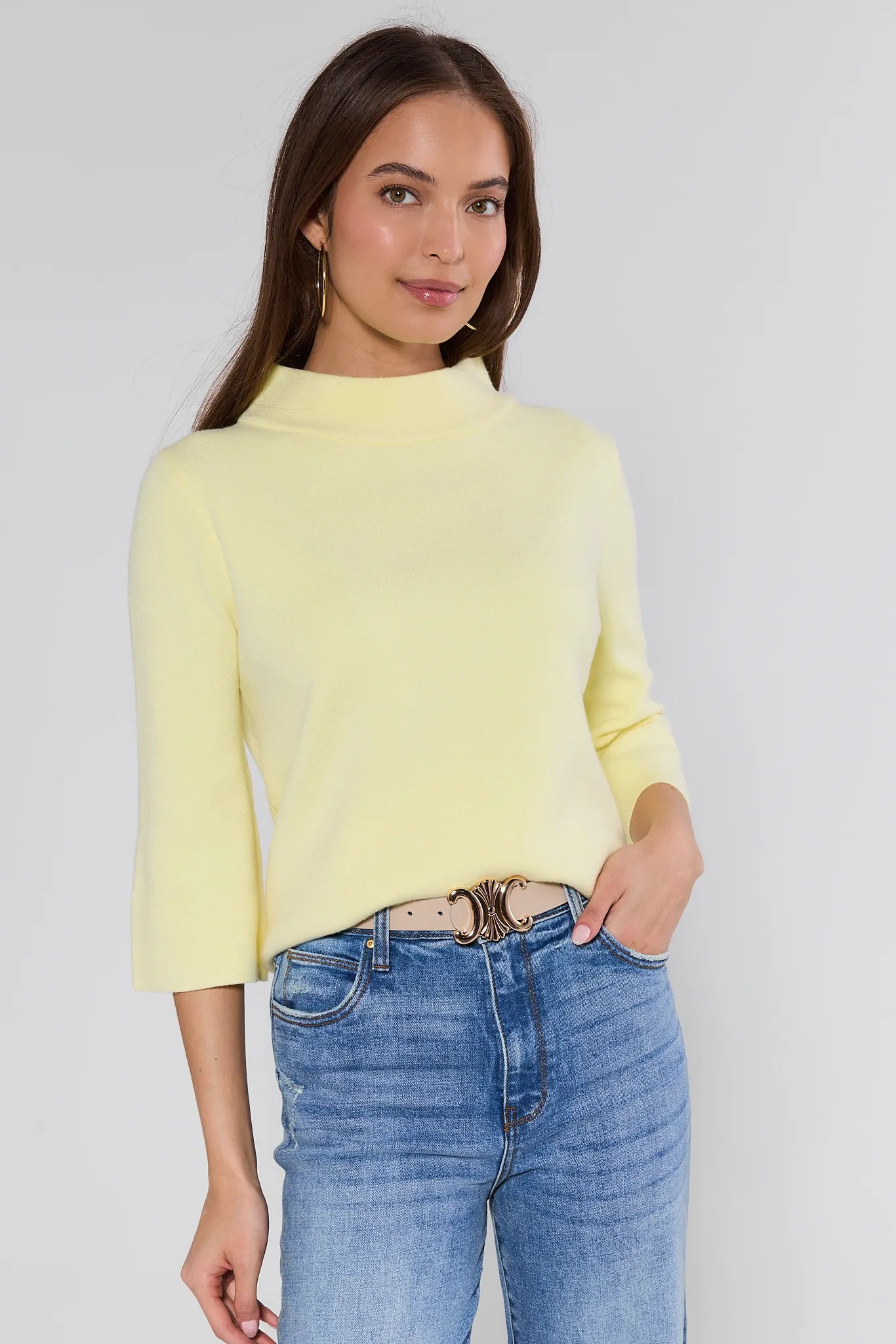 woman wearing a yellow jackie sweater on a white background