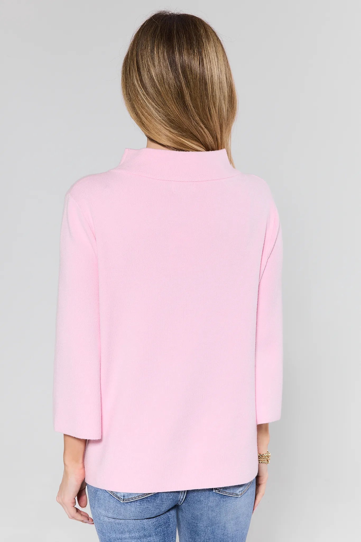 person wearing light pink sweater on white background