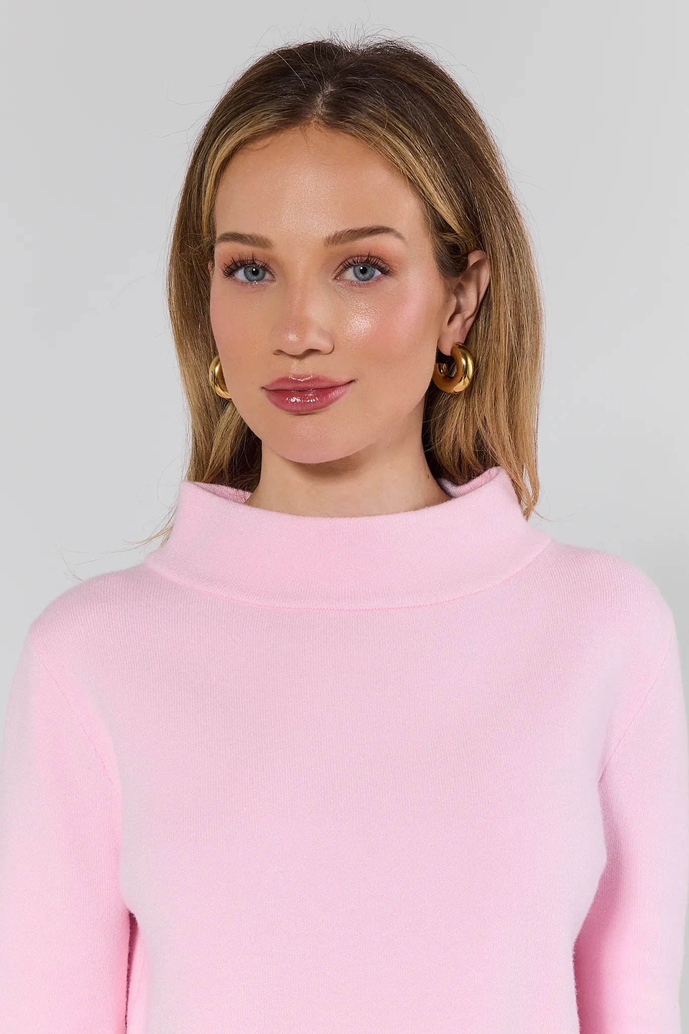 woman wearing light pink sweater on white background