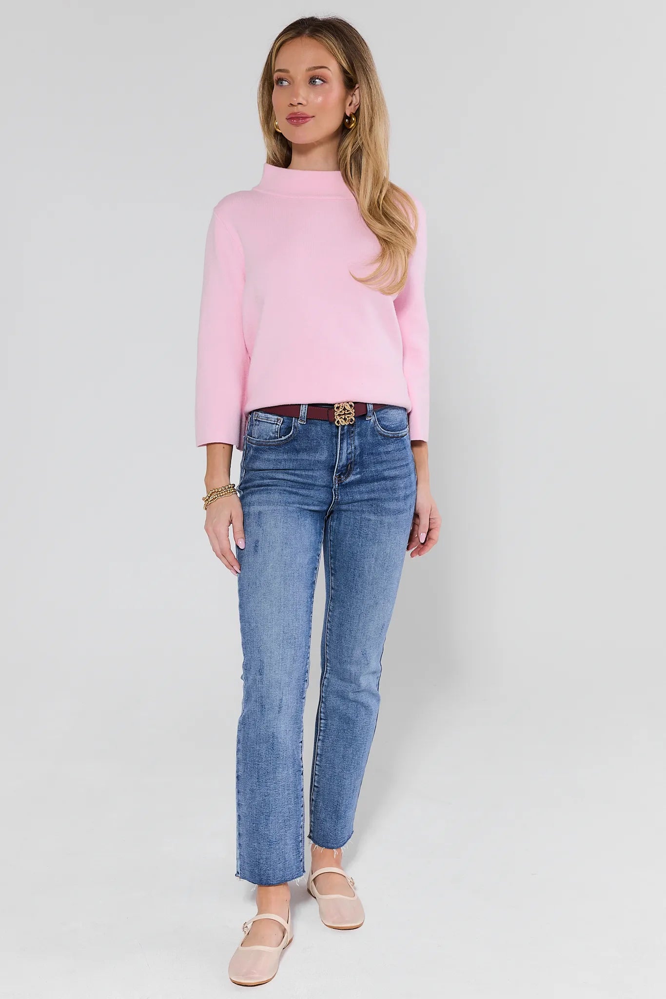 woman wearing light pink sweater and jeans on white background