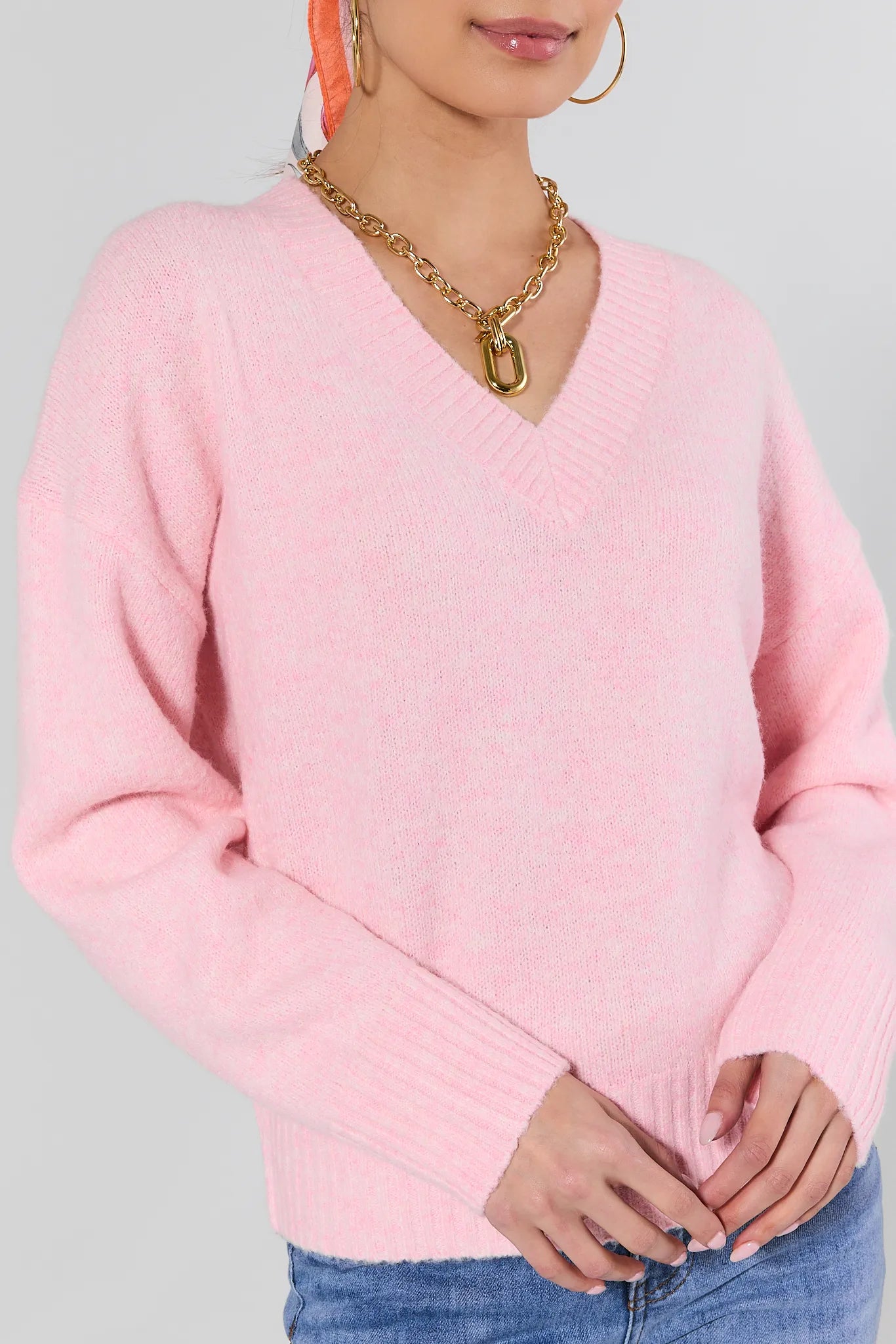 Person wearing a pink sweater with a plain background