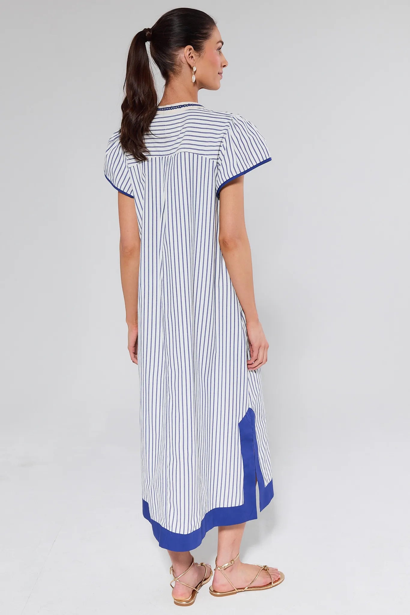 Woman wearing a white and blue striped dress on a gray background