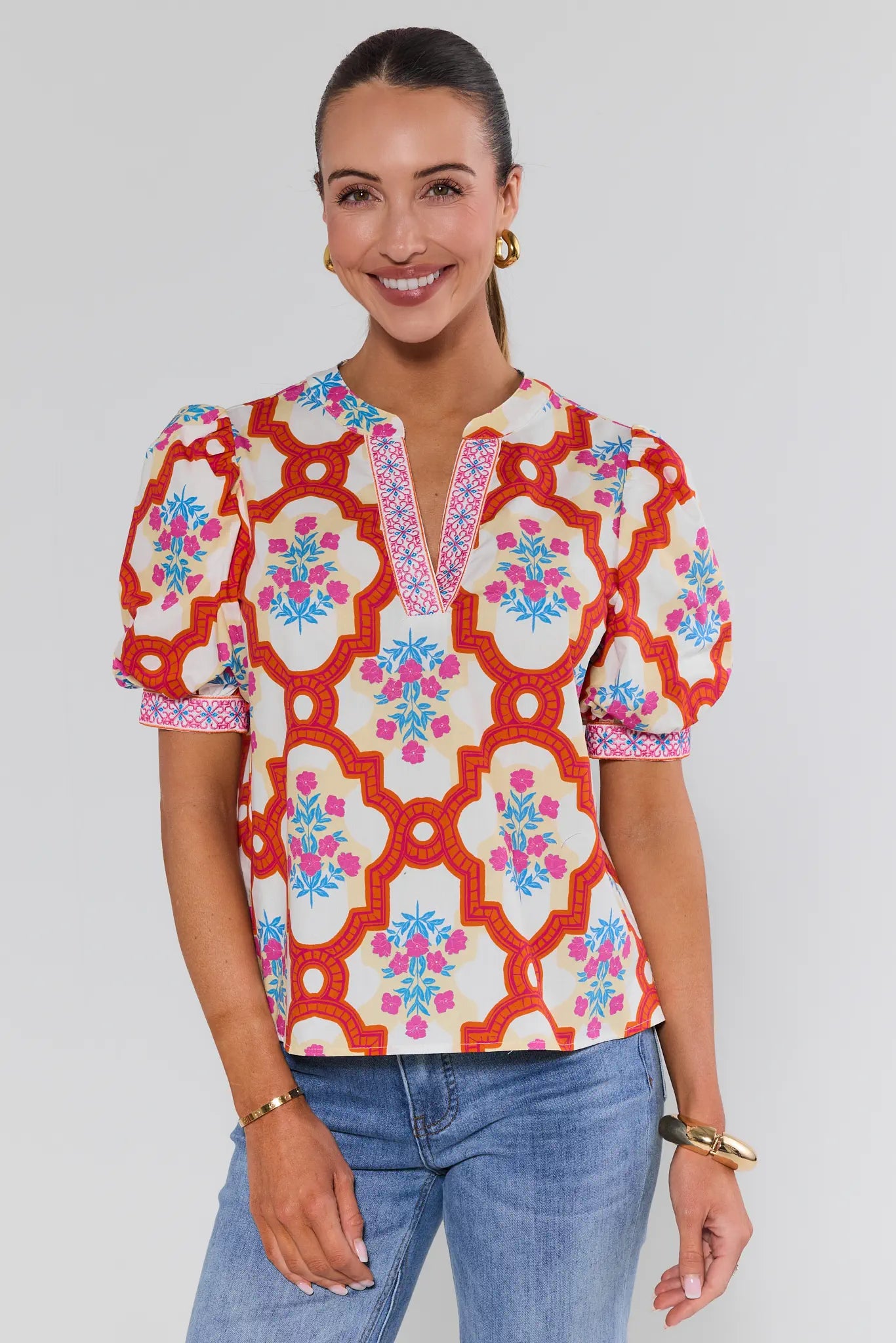 Woman wearing a colorful patterned blouse with a plain background