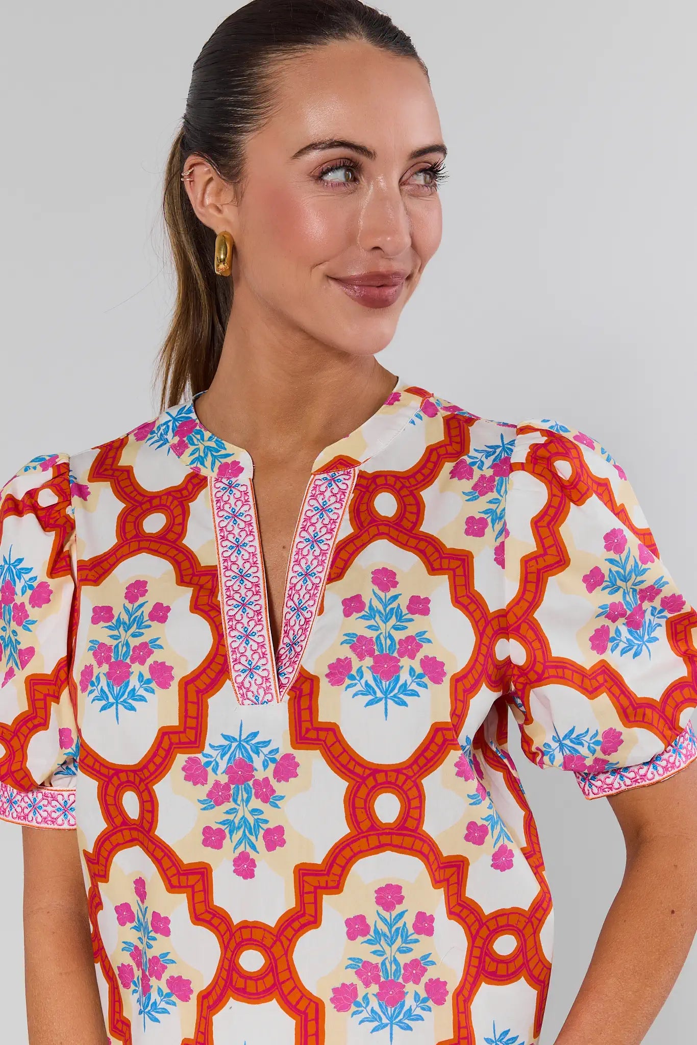 Woman wearing a colorful patterned dress against a plain background