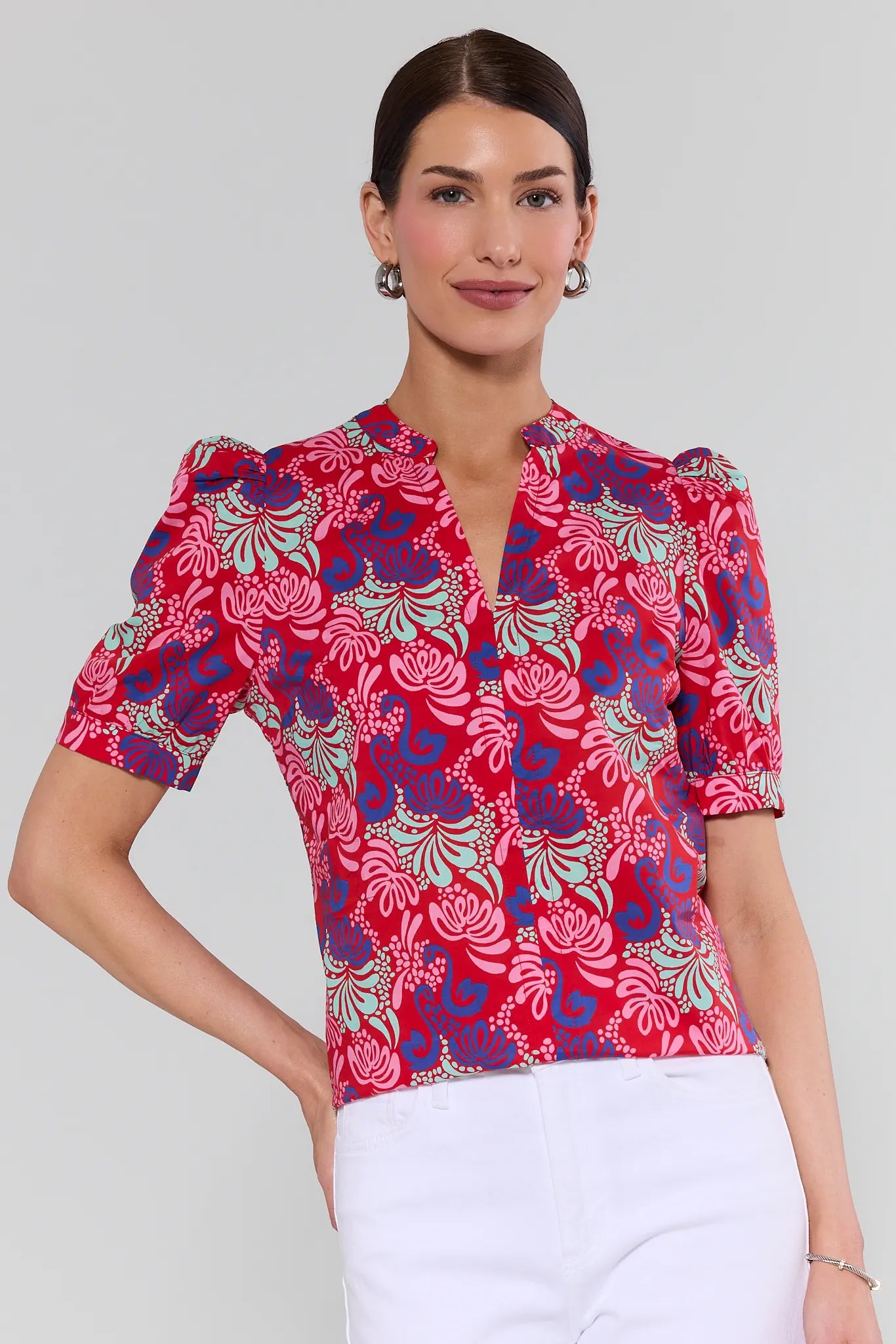 Woman wearing a red floral blouse against a plain background