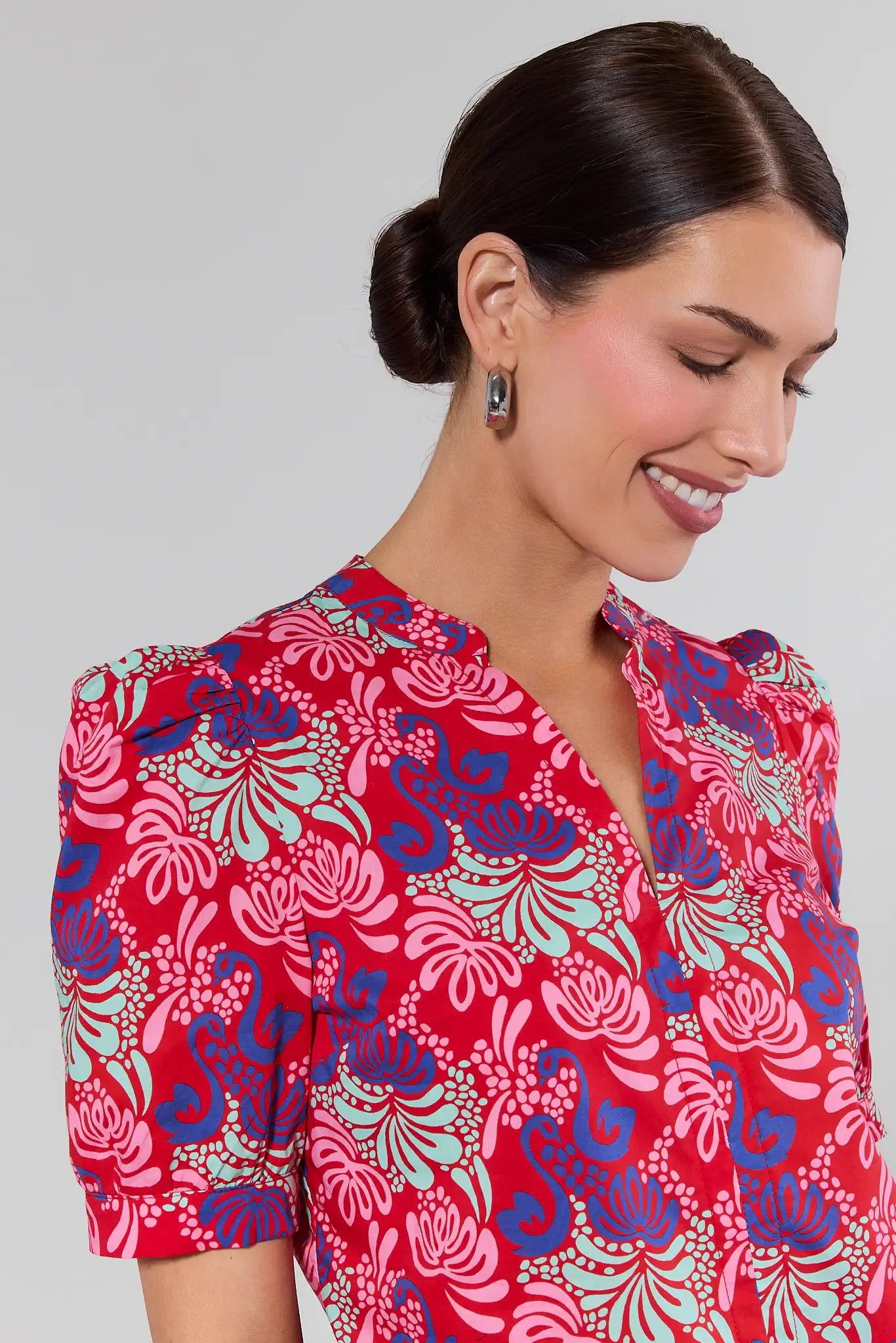 Woman wearing a red floral patterned blouse against a gray background