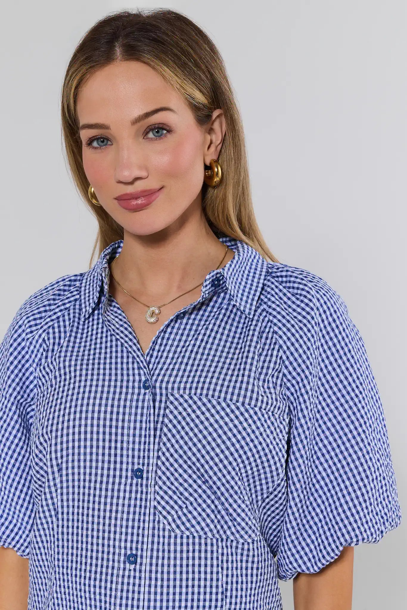 Woman wearing a blue checkered dress against a plain background