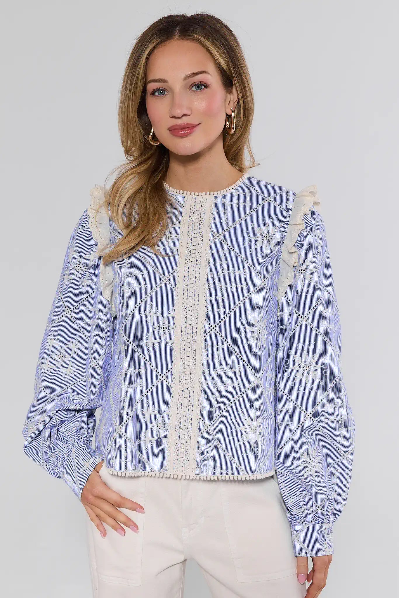 Woman wearing a blue and white patterned blouse with a plain background