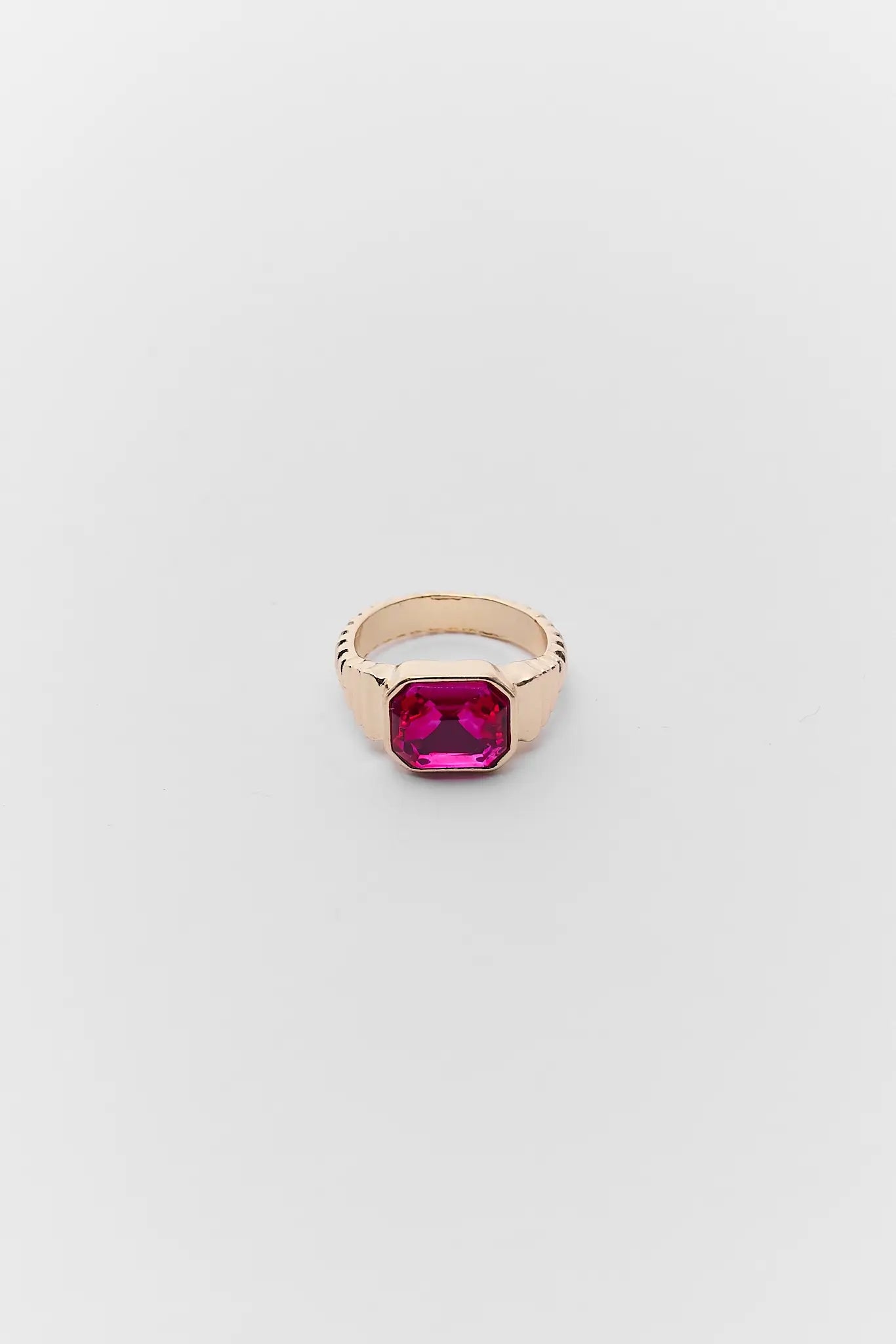 Gold ring with a pink gemstone on a light gray background