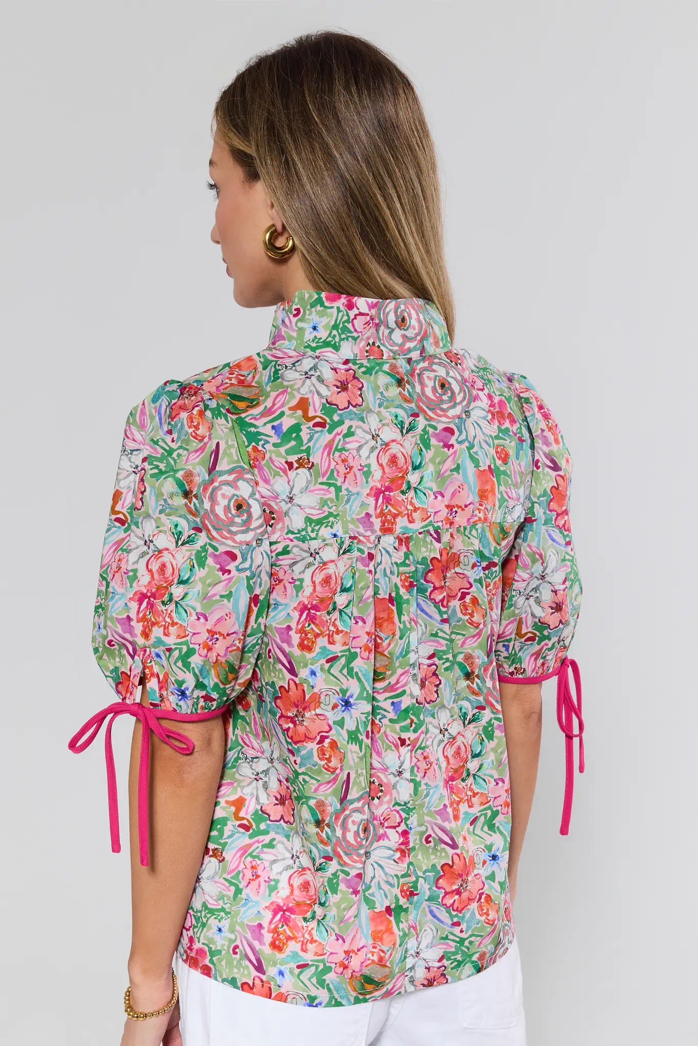 Woman wearing a colorful floral blouse with pink ties on a white background