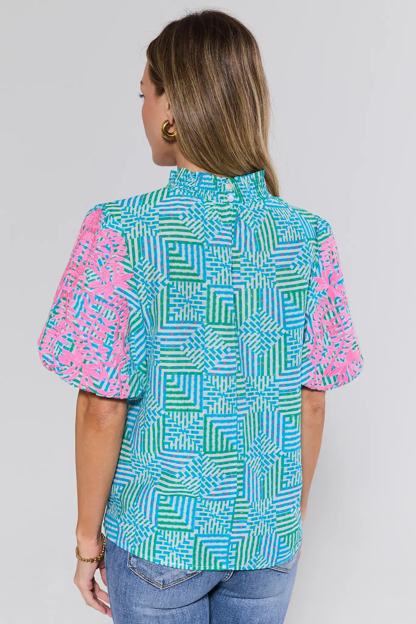 Woman wearing a colorful geometric patterned shirt on a plain background