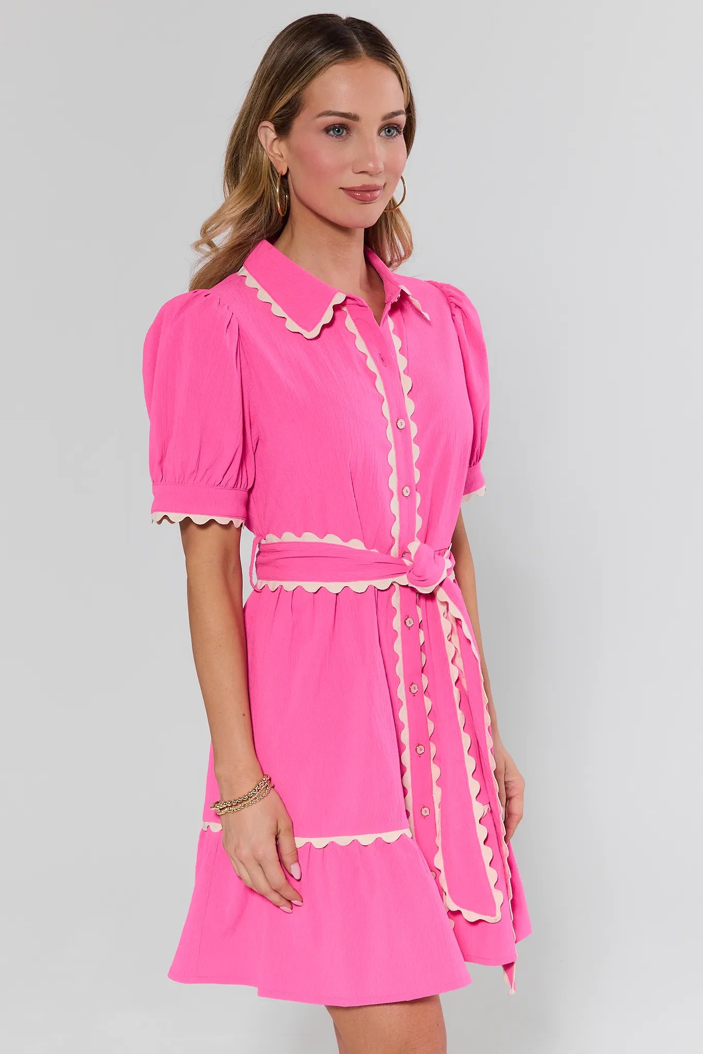 Woman wearing a pink dress with white trim on a gray background