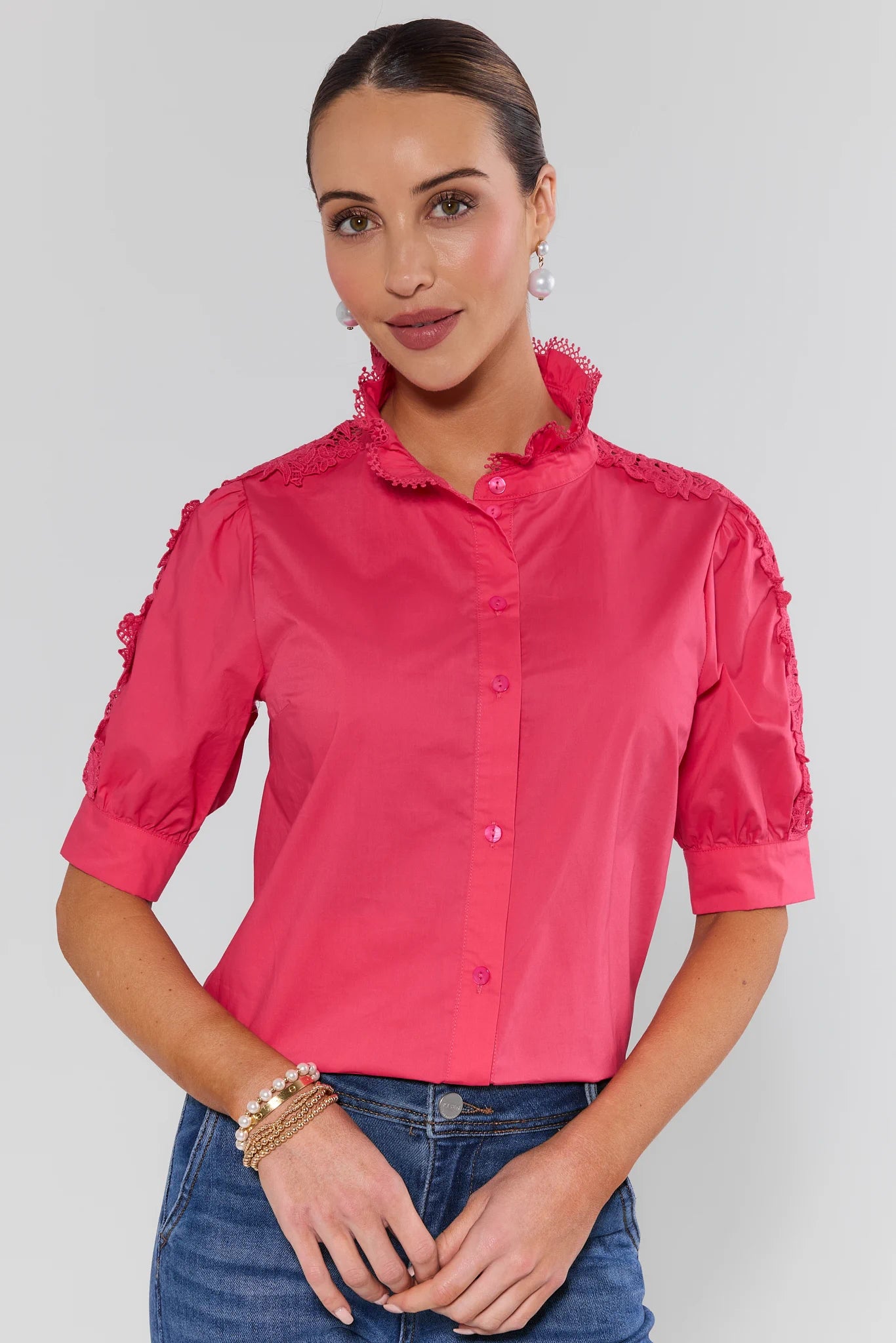 Woman wearing a pink blouse with ruffled details on a plain background