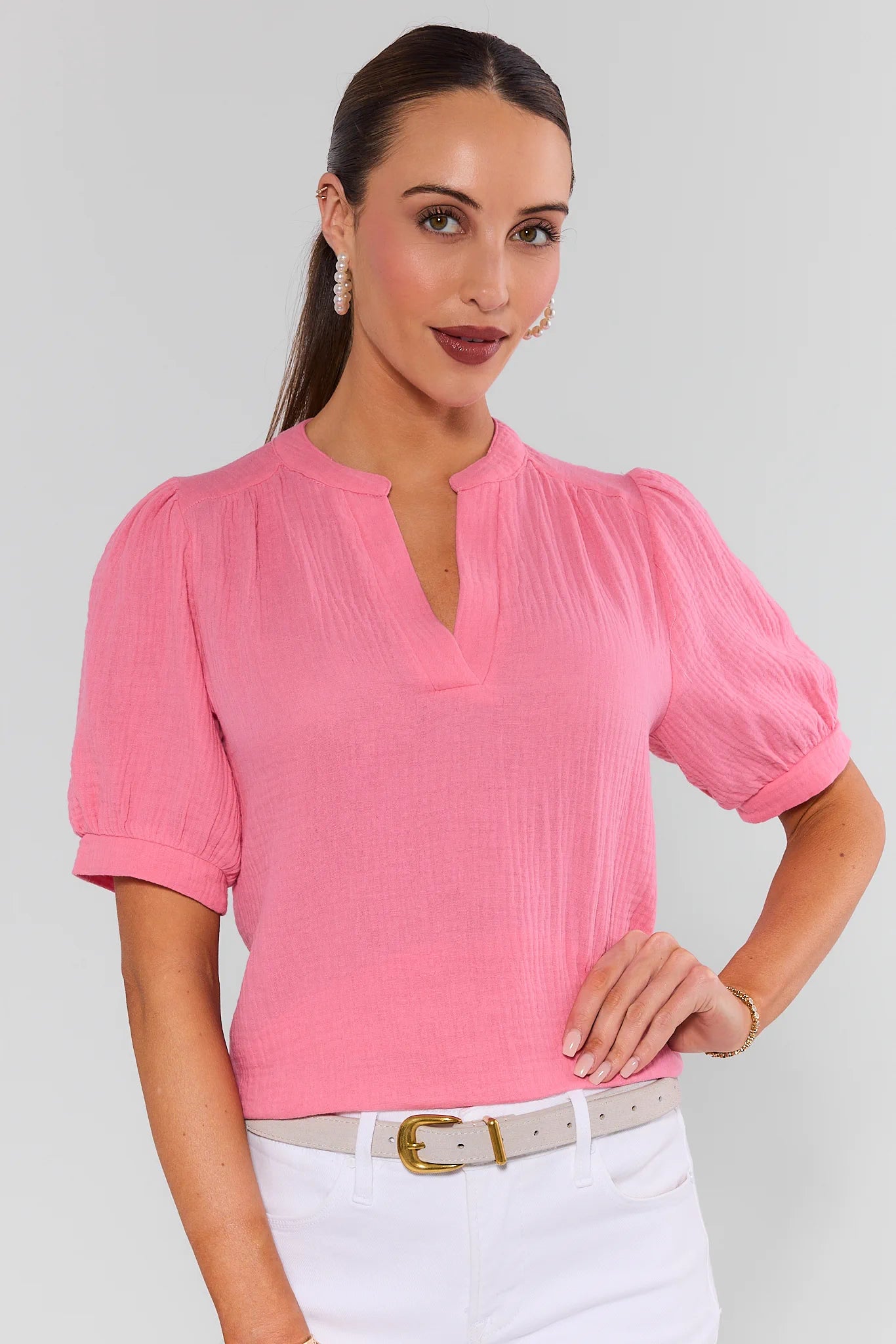 Woman wearing a pink blouse with puff sleeves on a light gray background