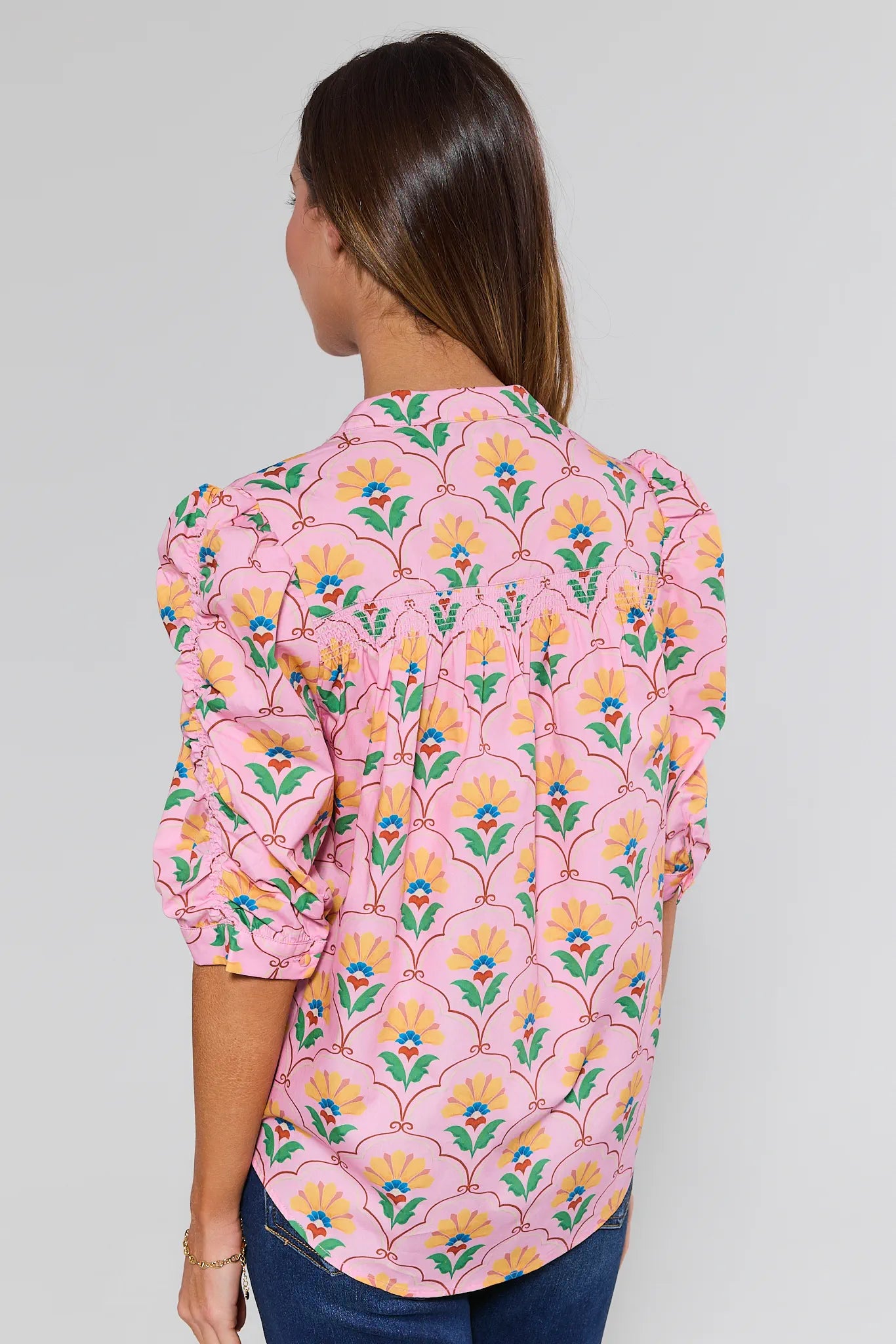 Woman wearing a pink floral blouse against a gray background