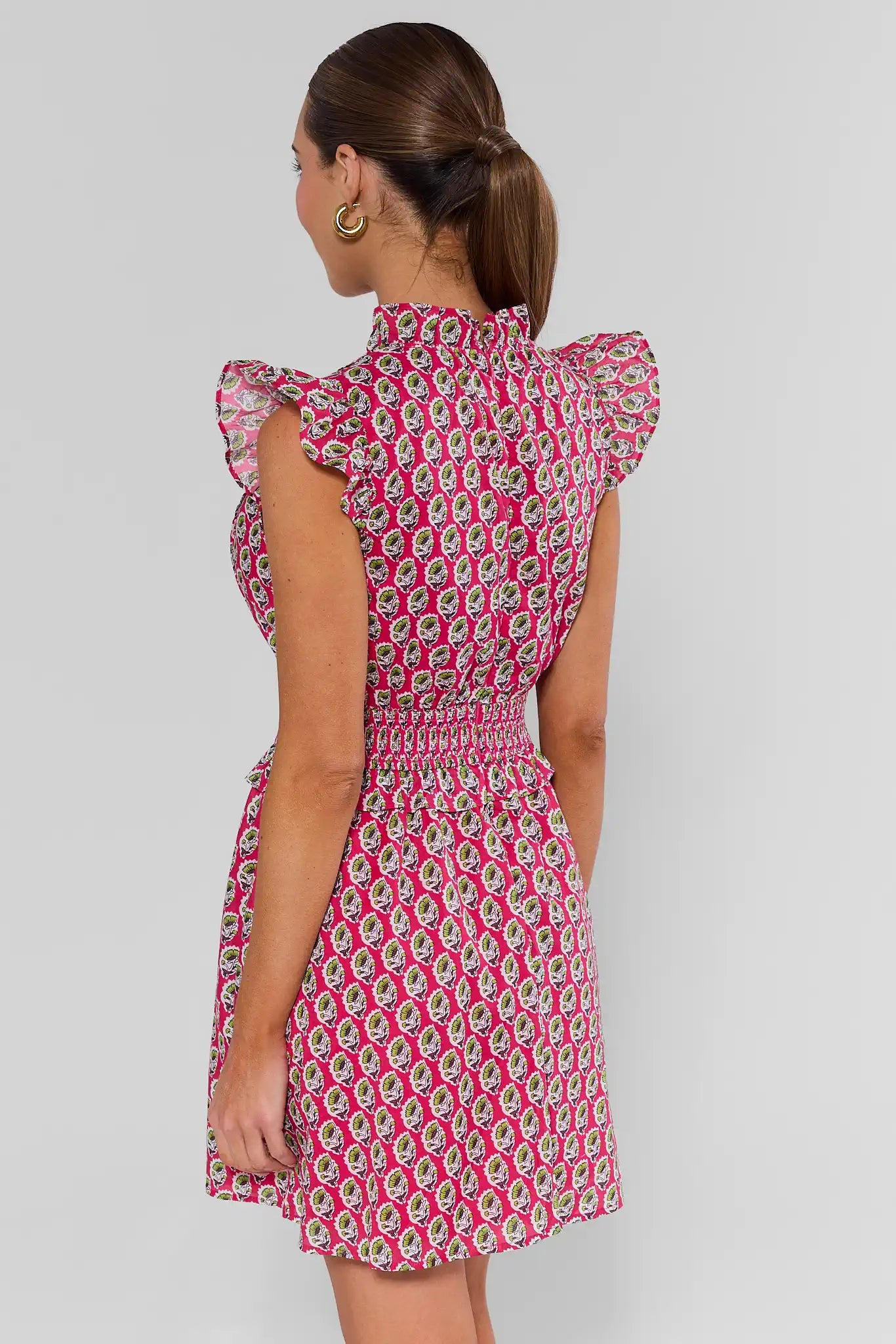 Woman wearing a pink patterned dress on a plain background