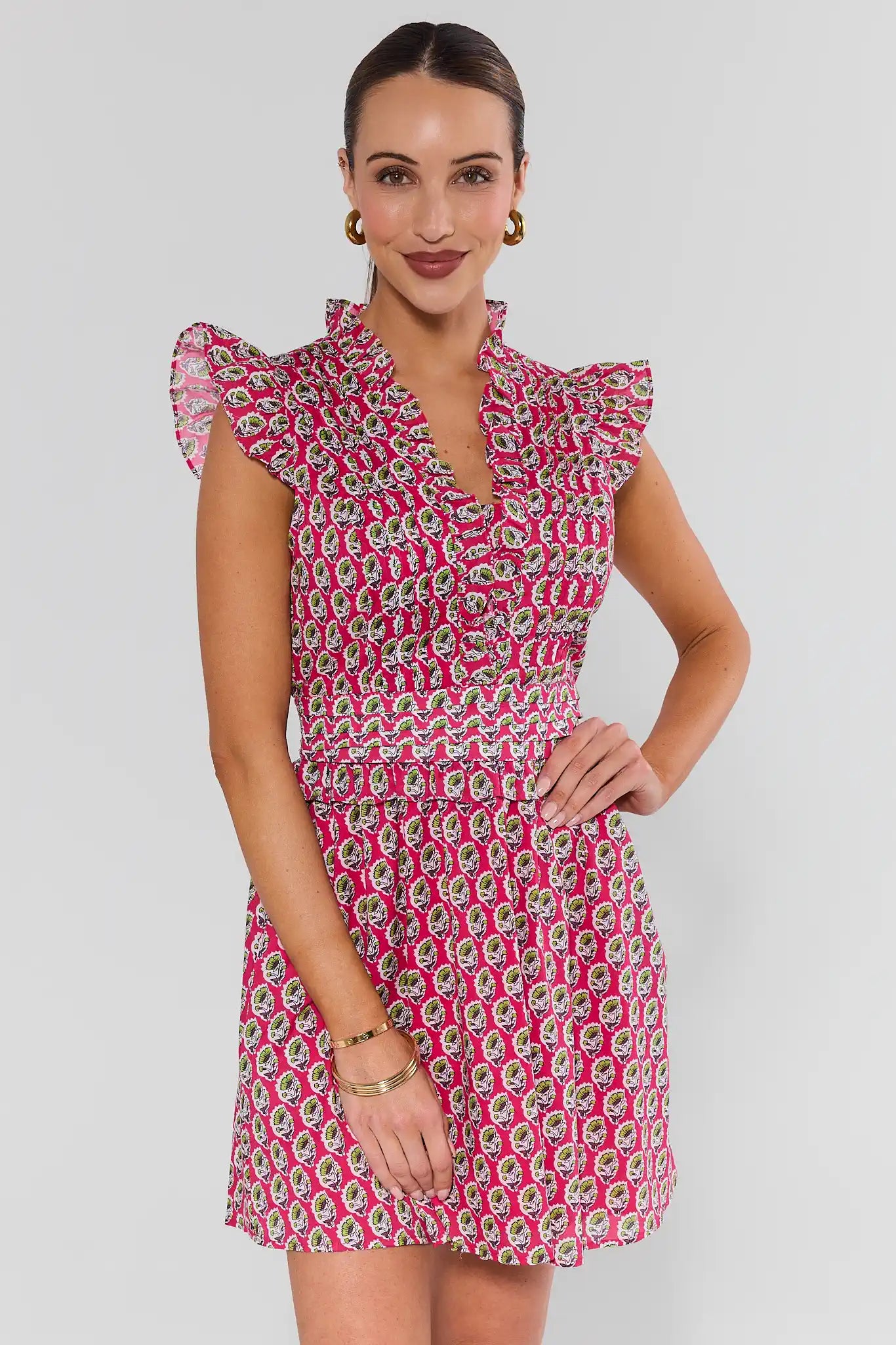 Woman wearing a pink and white patterned dress on a plain background