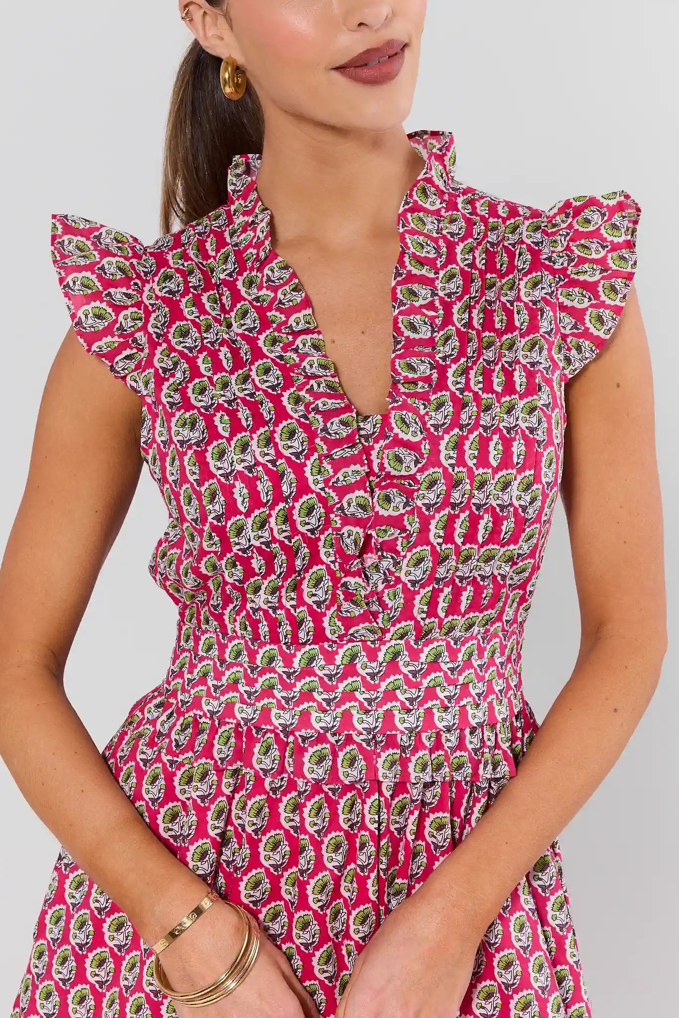 Woman wearing a pink dress with a floral pattern on a plain background