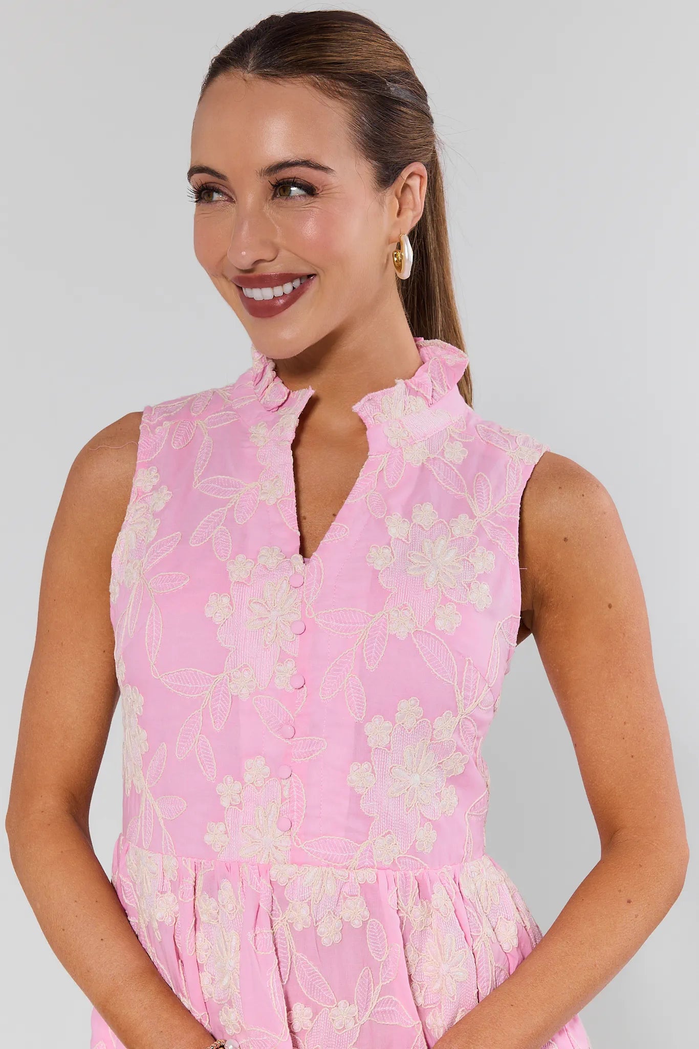 Woman wearing a pink floral dress against a plain background