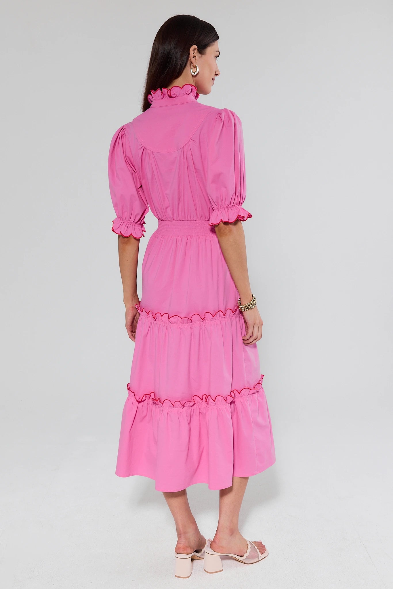 Woman wearing a pink dress with ruffled details on a white background