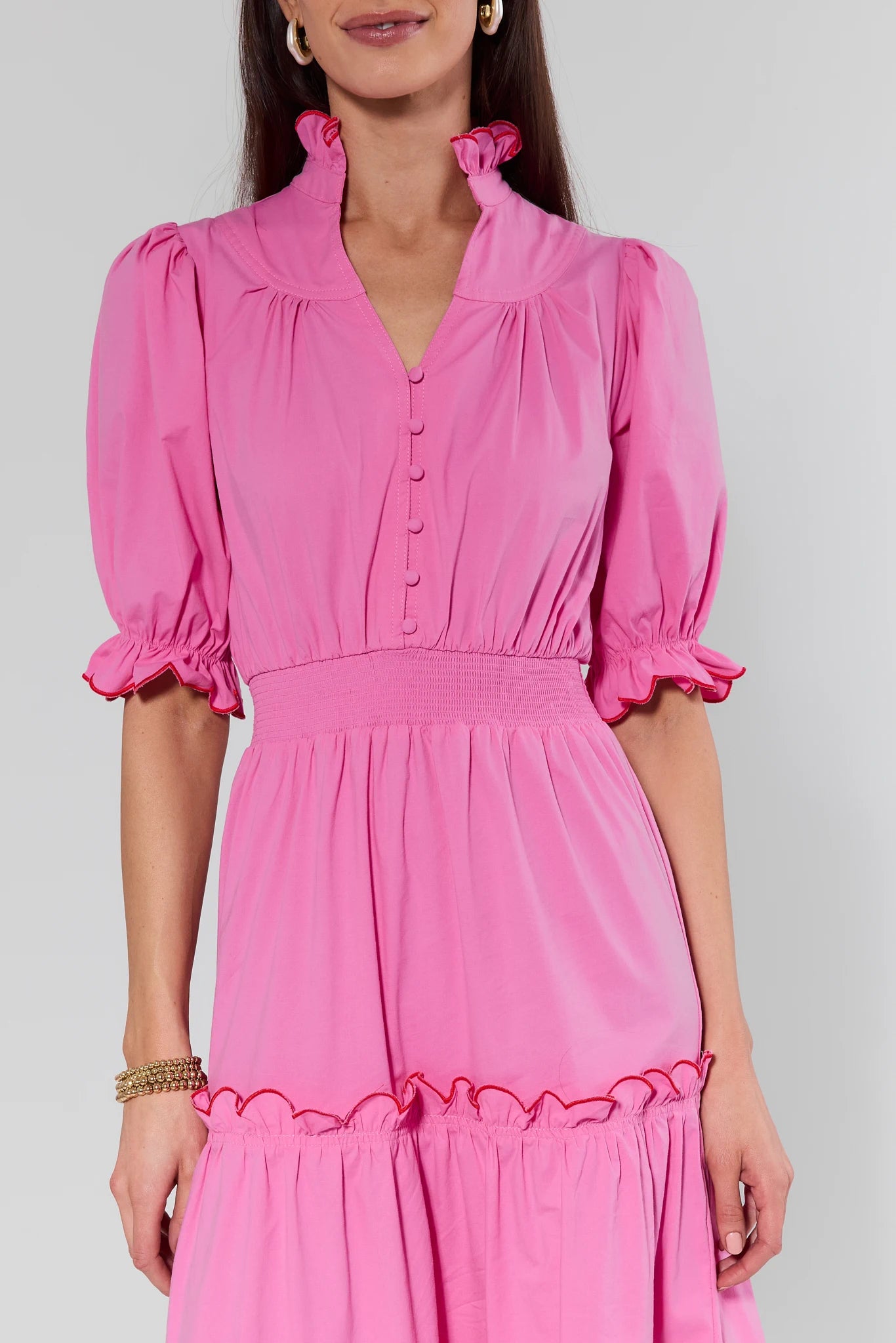 Woman wearing a pink dress with puffed sleeves on a gray background