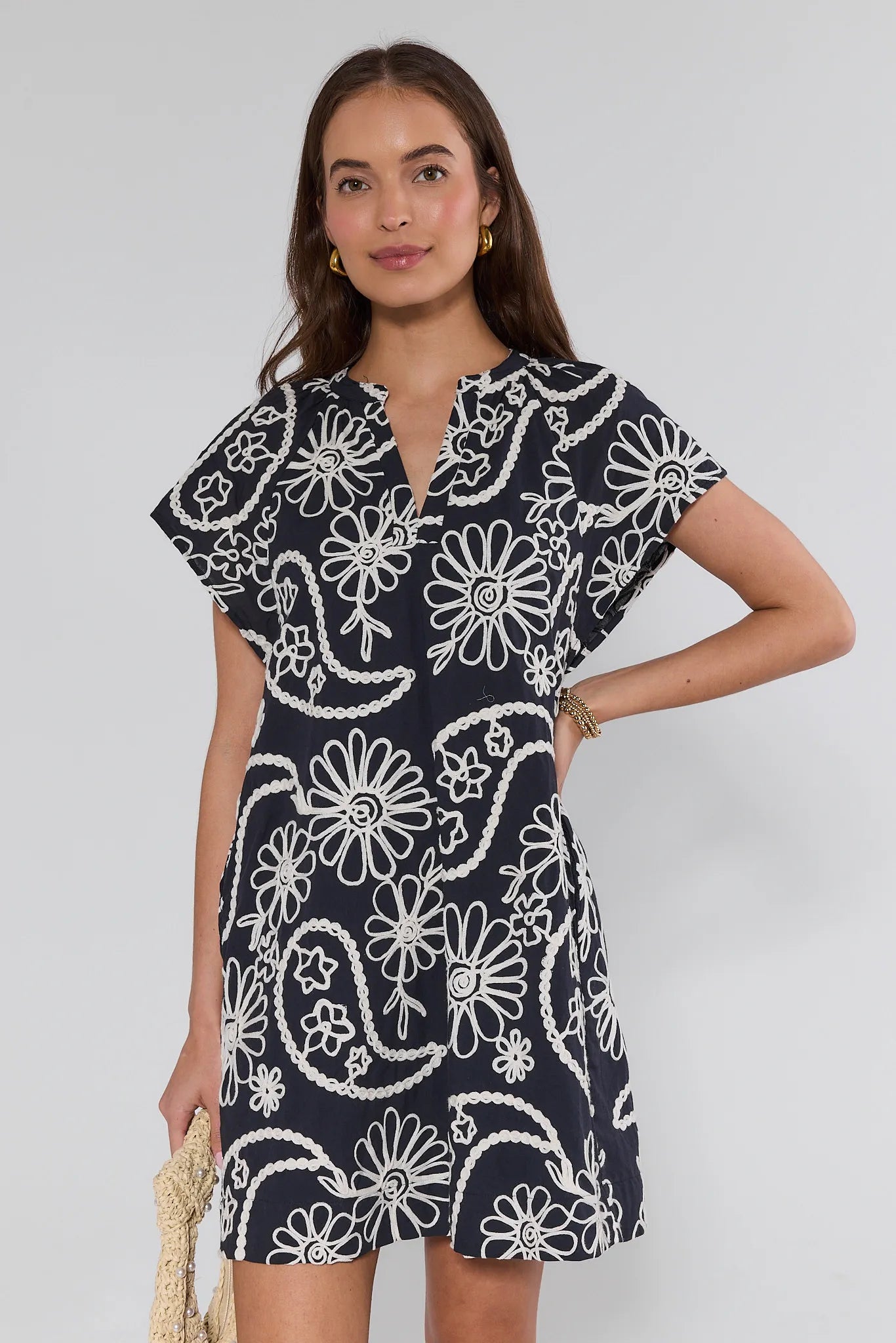 Woman wearing a navy dress with white floral pattern against a white background