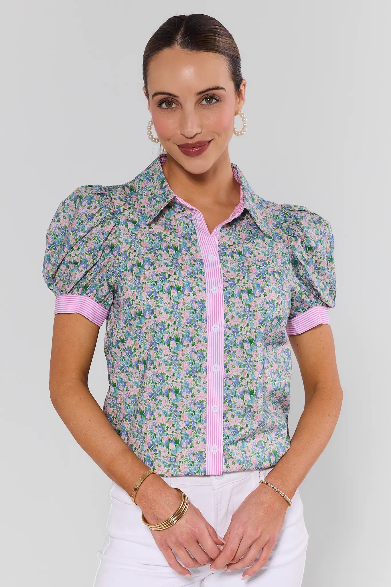 Woman wearing a floral blouse with pink accents on a white background