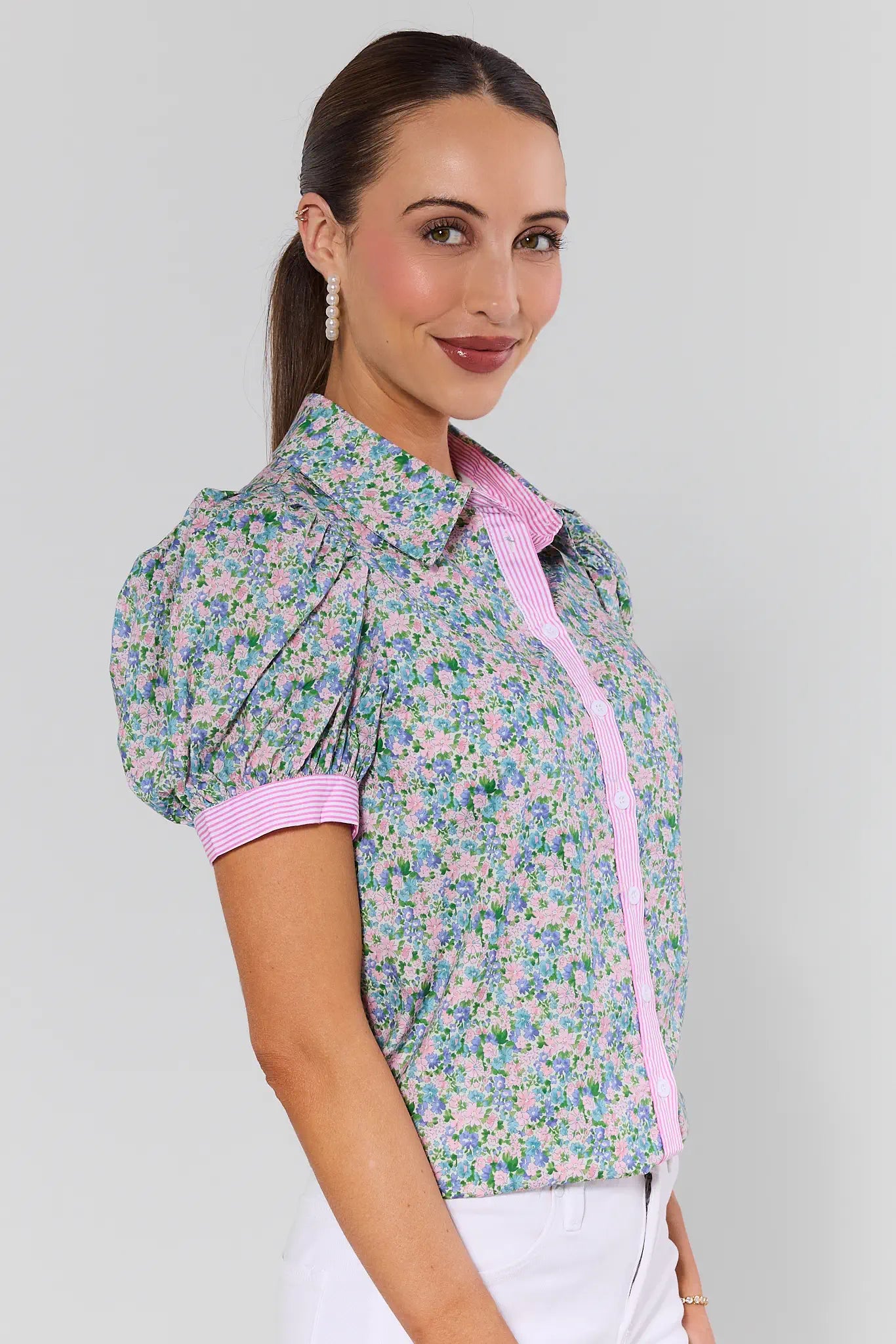 Woman wearing a floral blouse with pink trim on a gray background