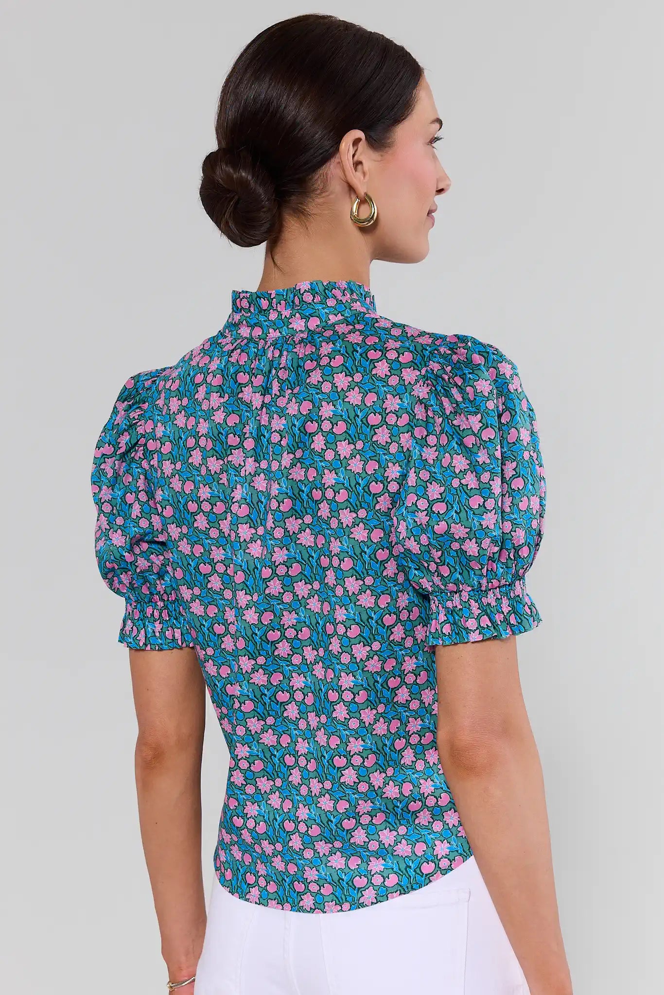 Woman wearing a teal floral blouse against a plain background