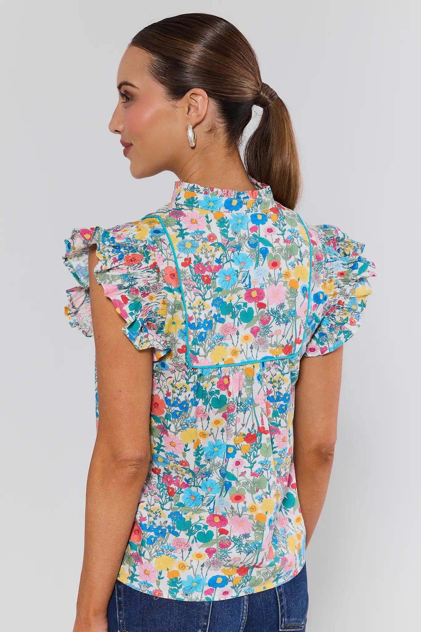 Woman wearing a colorful floral blouse against a plain background