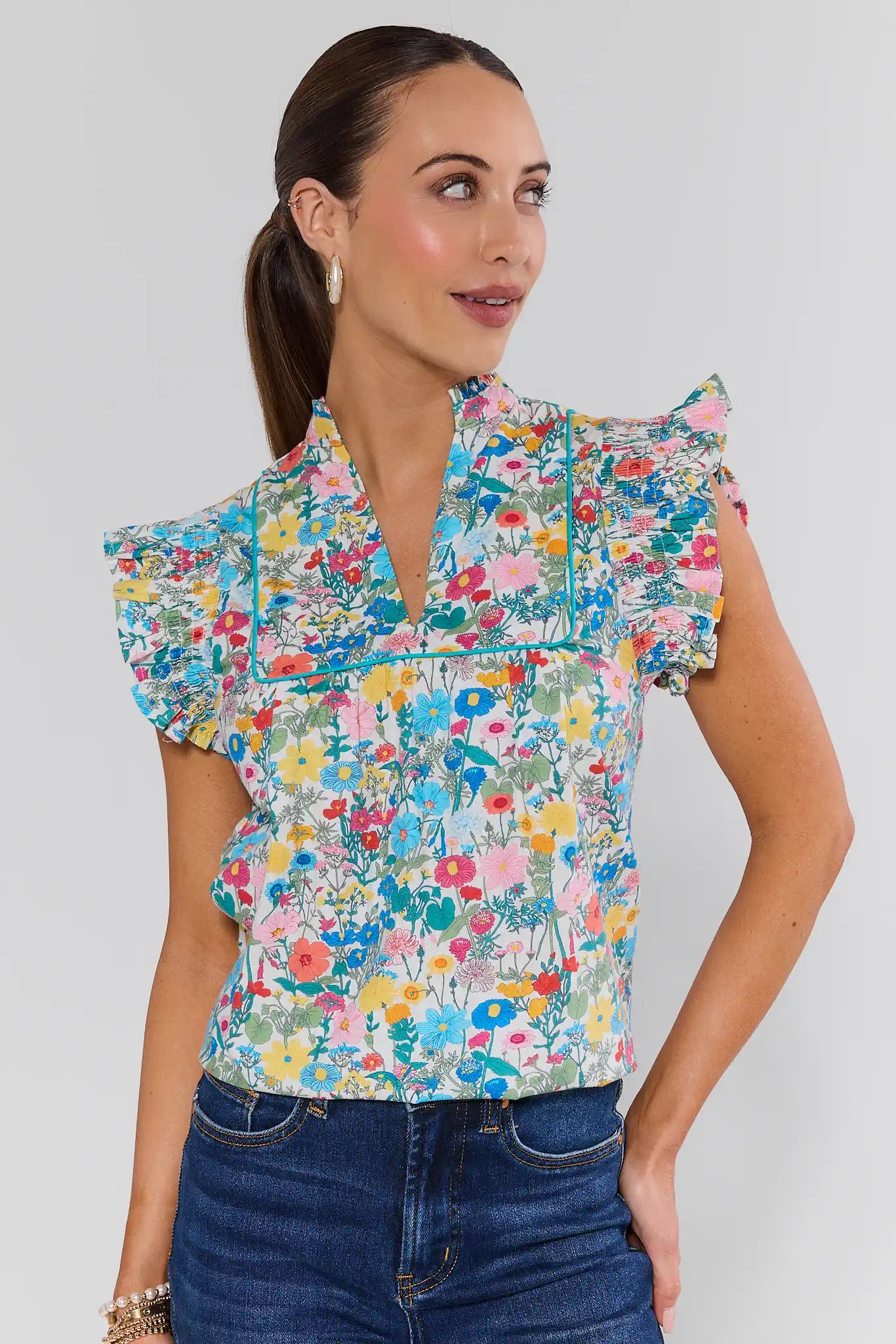 Woman wearing a colorful floral blouse with ruffled sleeves on a white background