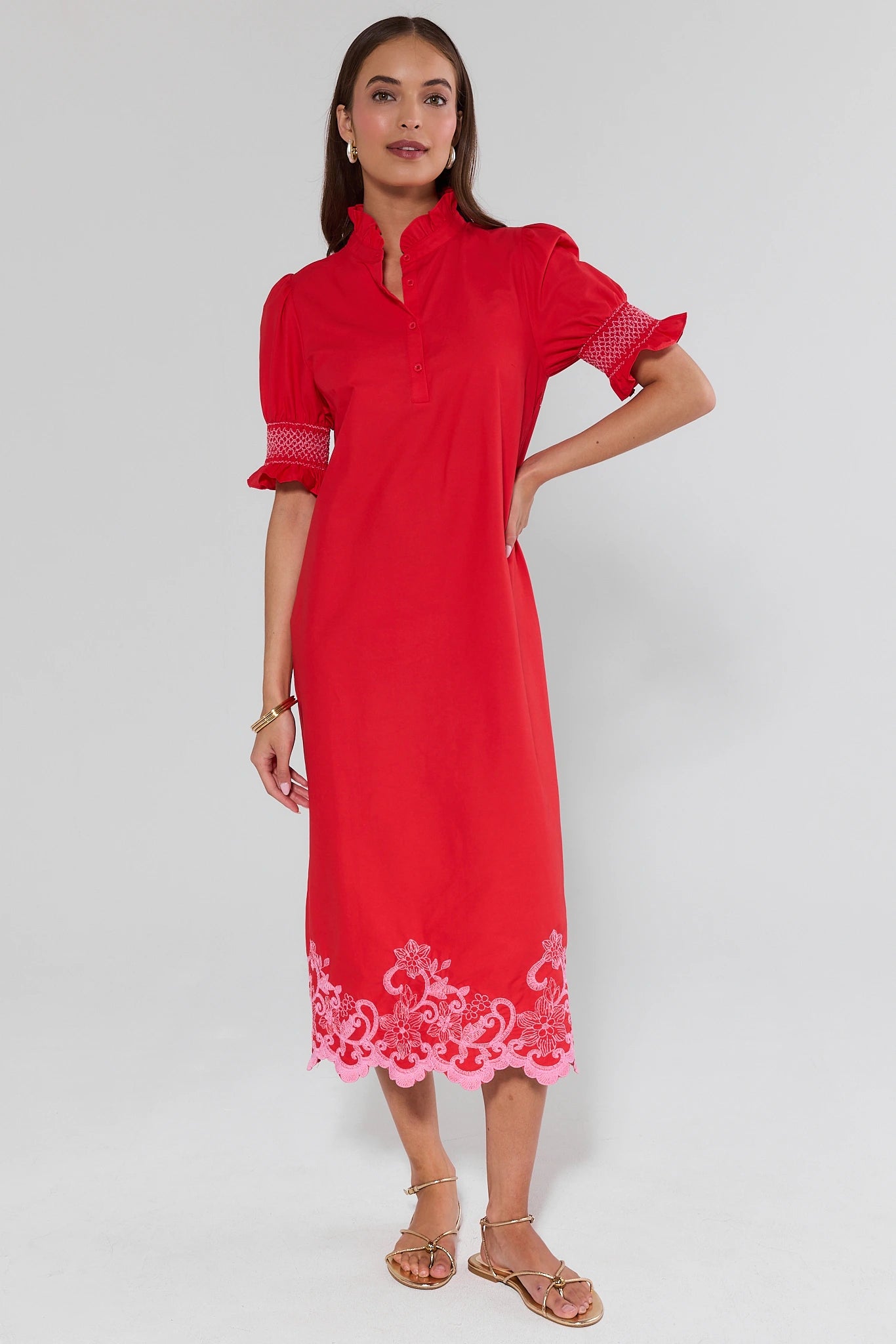 Woman wearing a red dress with white embroidery on a white background
