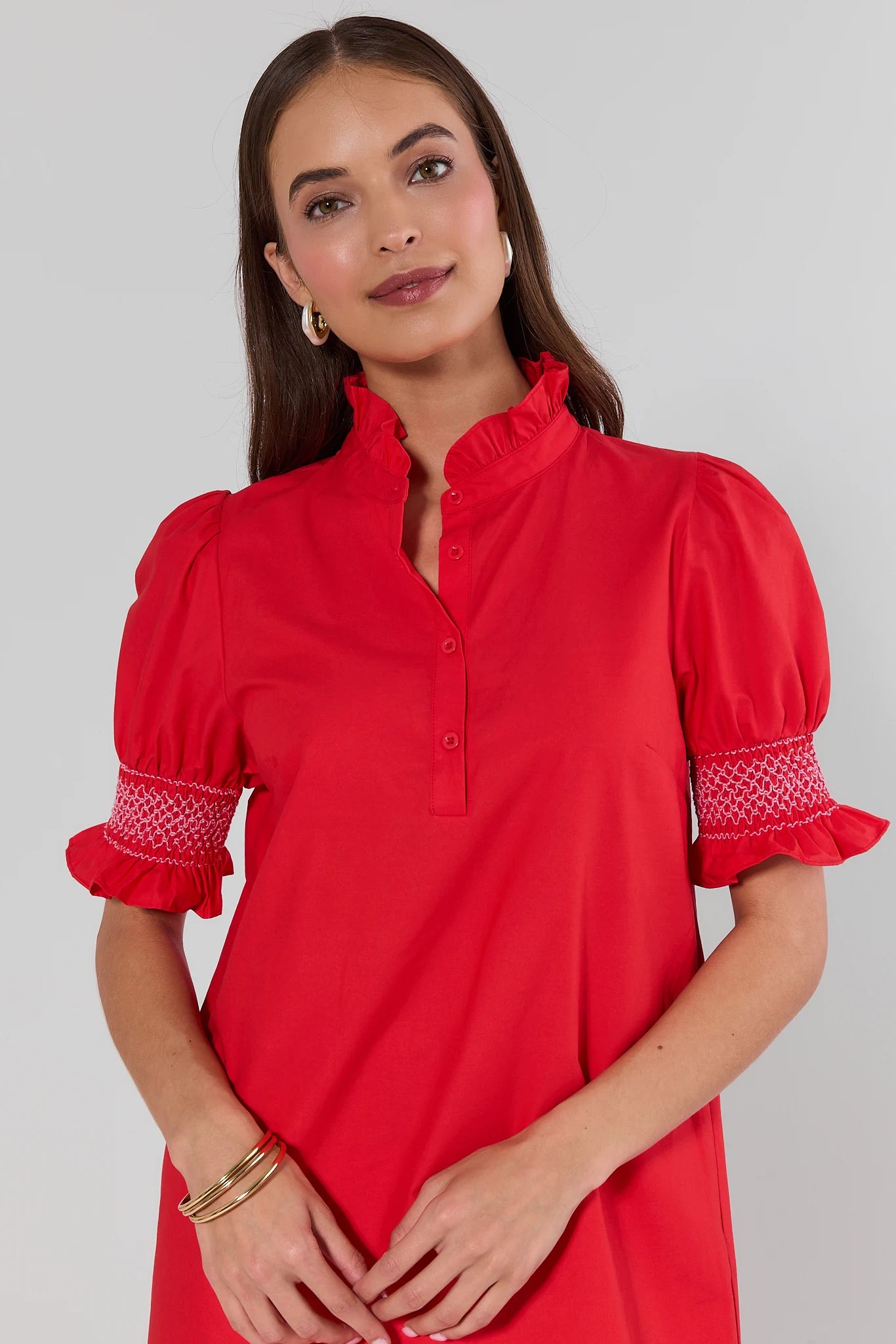 Woman wearing a red dress with embroidered details on a gray background