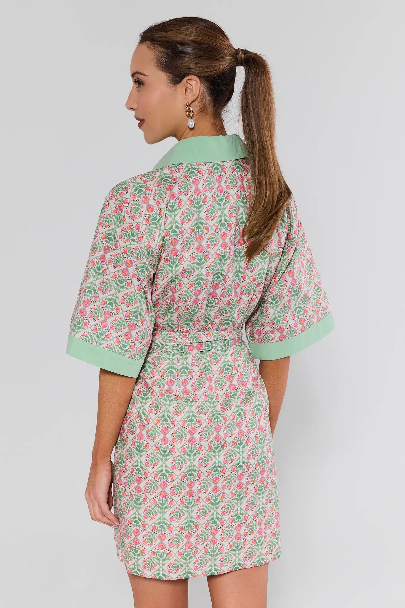 Woman wearing a floral dress with green accents on a plain background