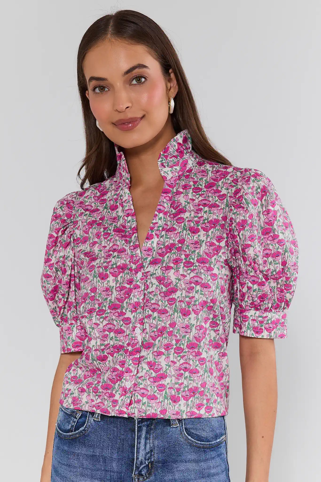 Woman wearing a pink floral blouse with blue jeans against a white background