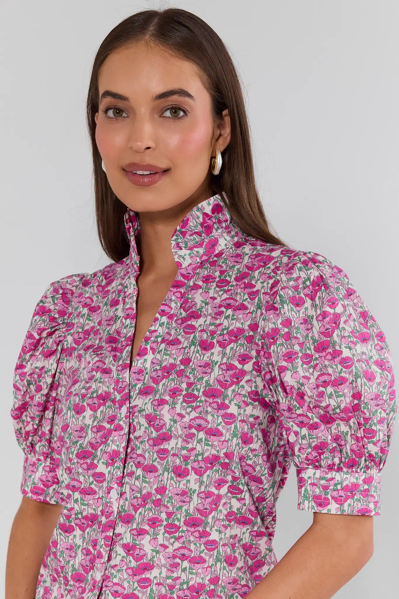 Woman wearing a pink floral dress against a plain background
